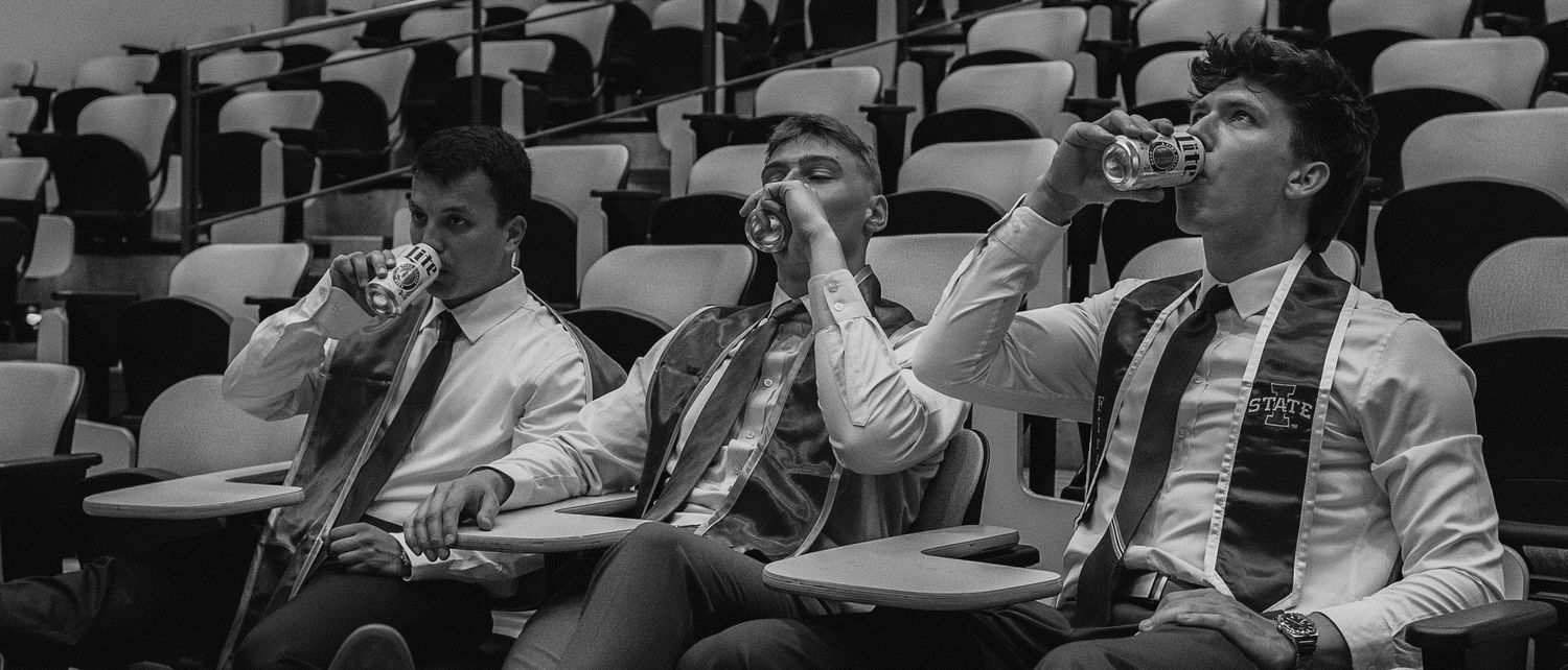 Students in an empty lecture hall using their phones in black and white.