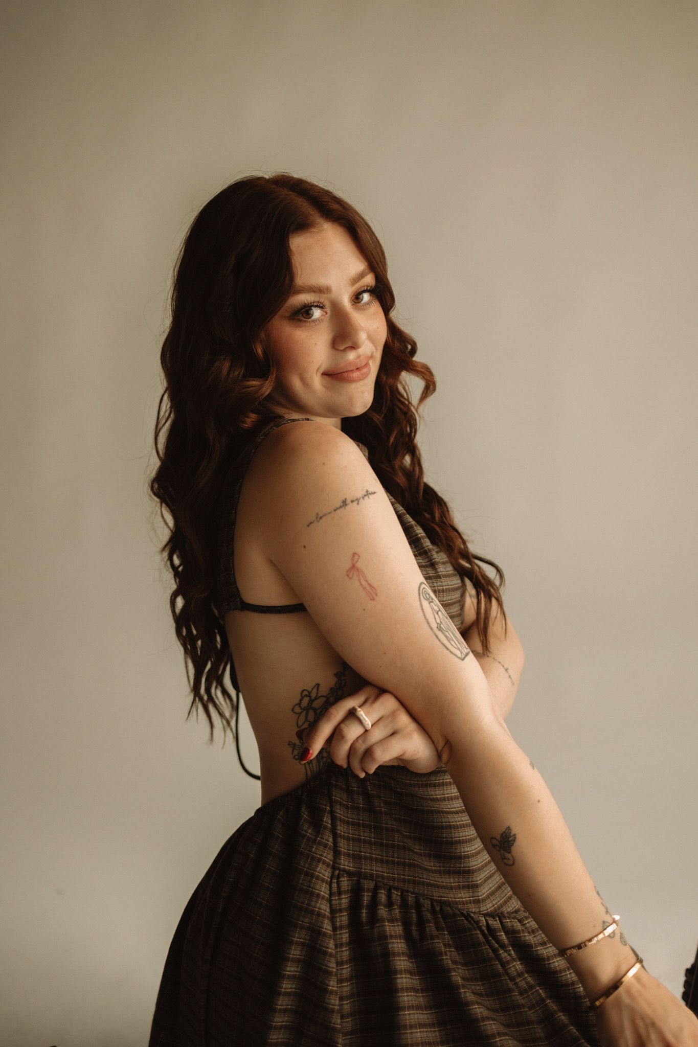 Woman in striped dress poses against beige wall in artistic portrait series showing various angles.