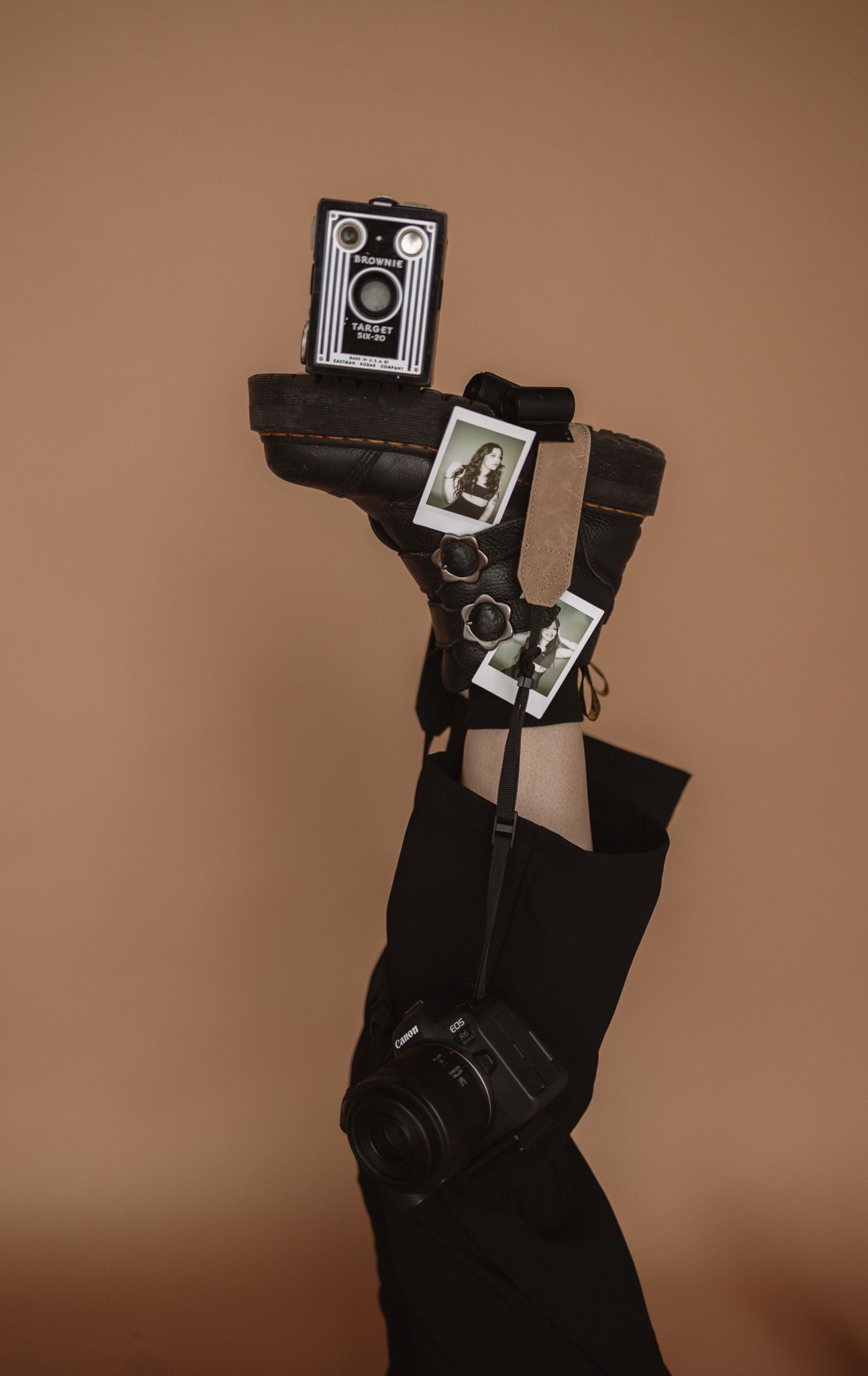 Vintage cameras held aloft against a brown backdrop create an artistic photography-themed composition.