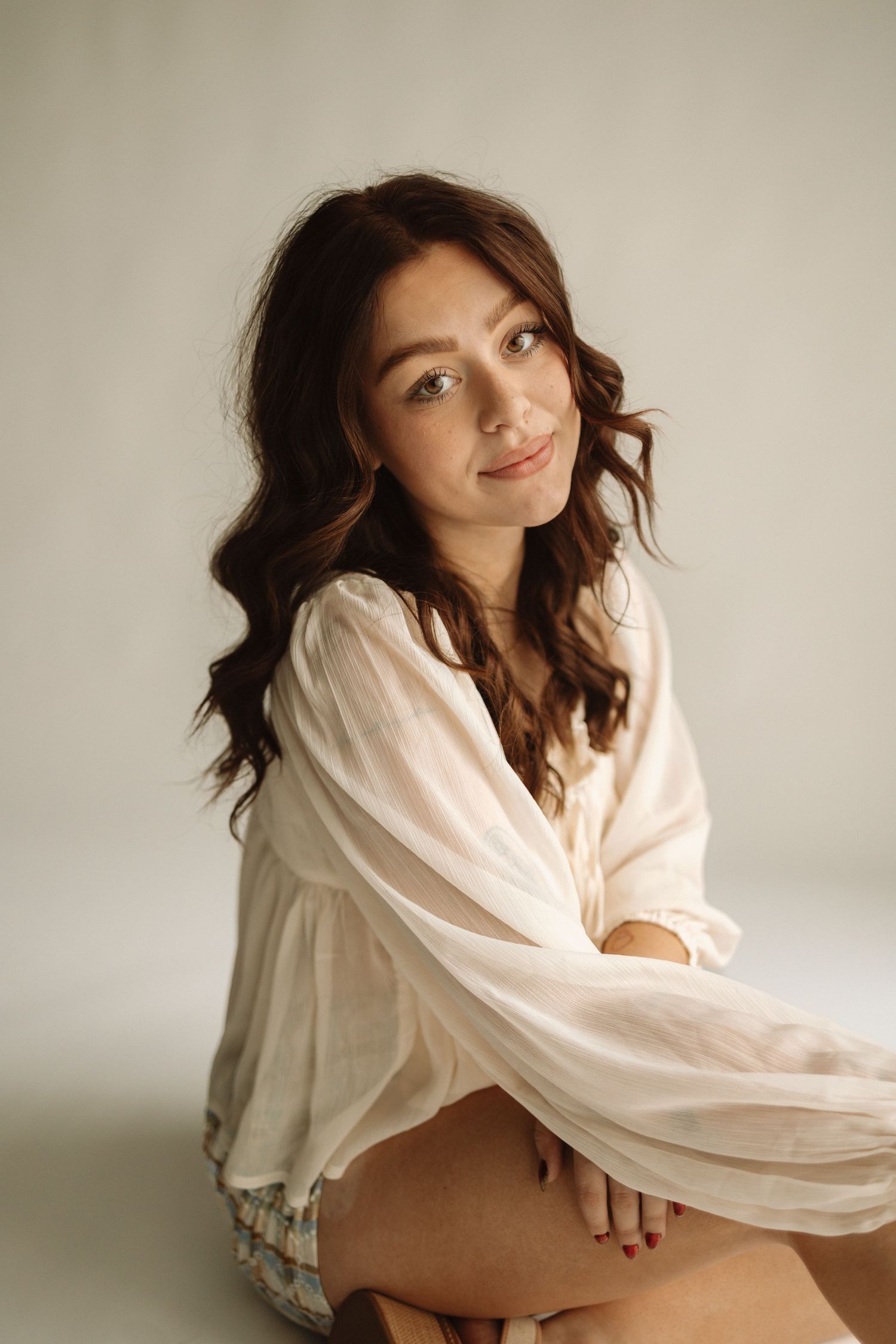 A series of artistic portrait photos featuring someone in flowing white fabric posing gracefully against a neutral backdrop.