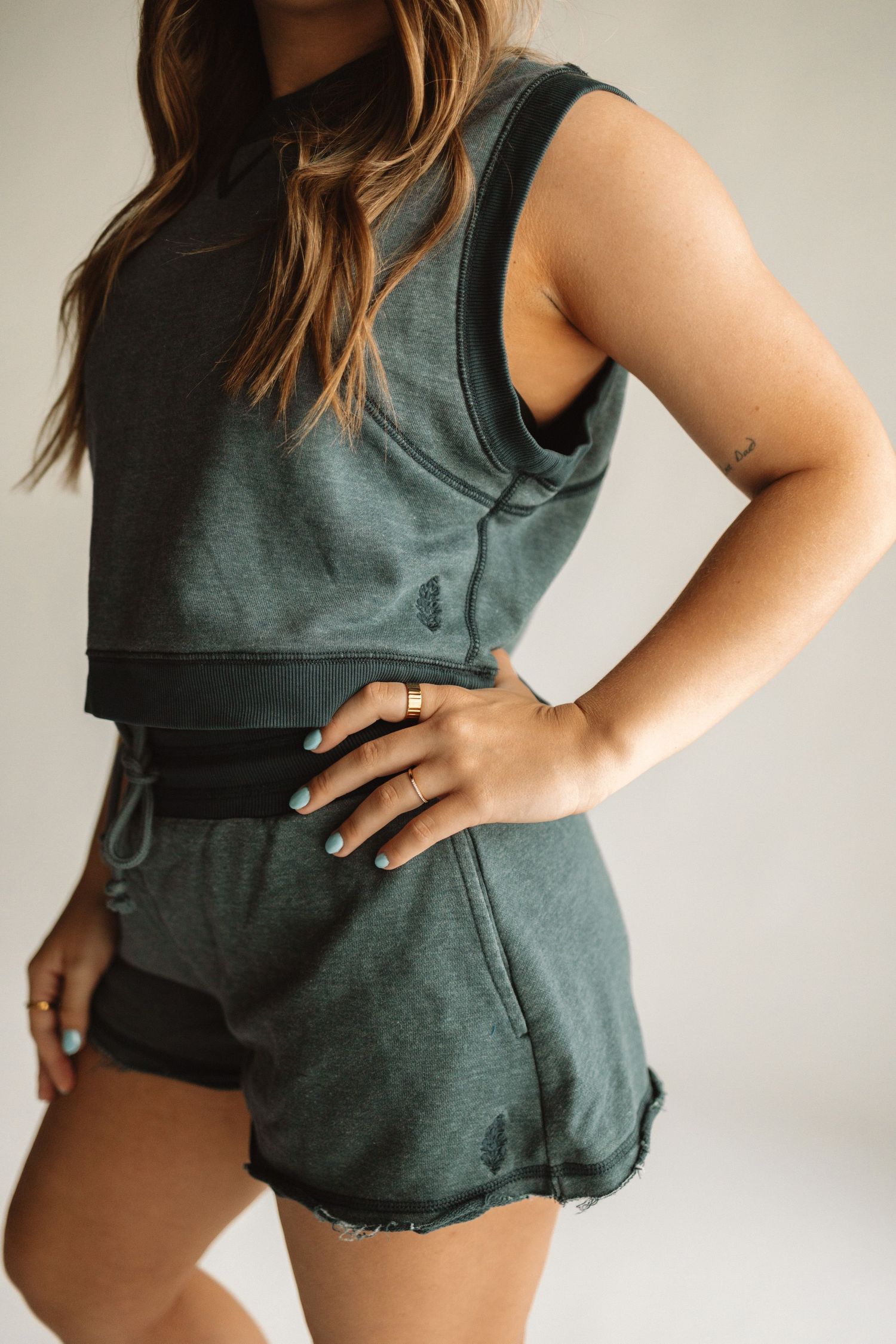 Woman in dark green linen romper with shorts style bottom and sleeveless top shown from different angles.