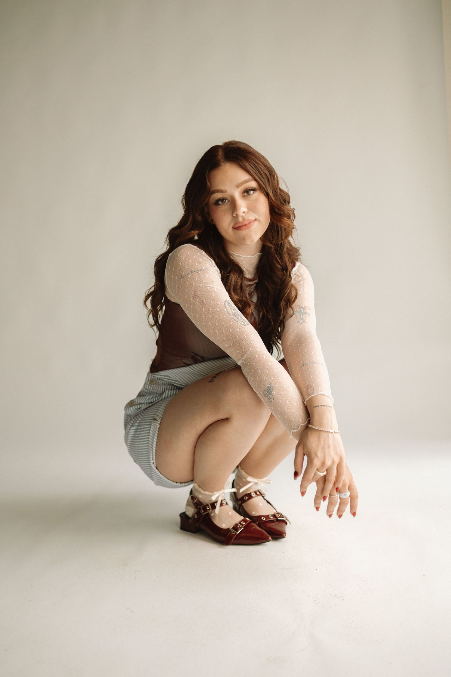 A series of minimalist studio portraits showing a person in casual clothing sitting and posing against a white background.