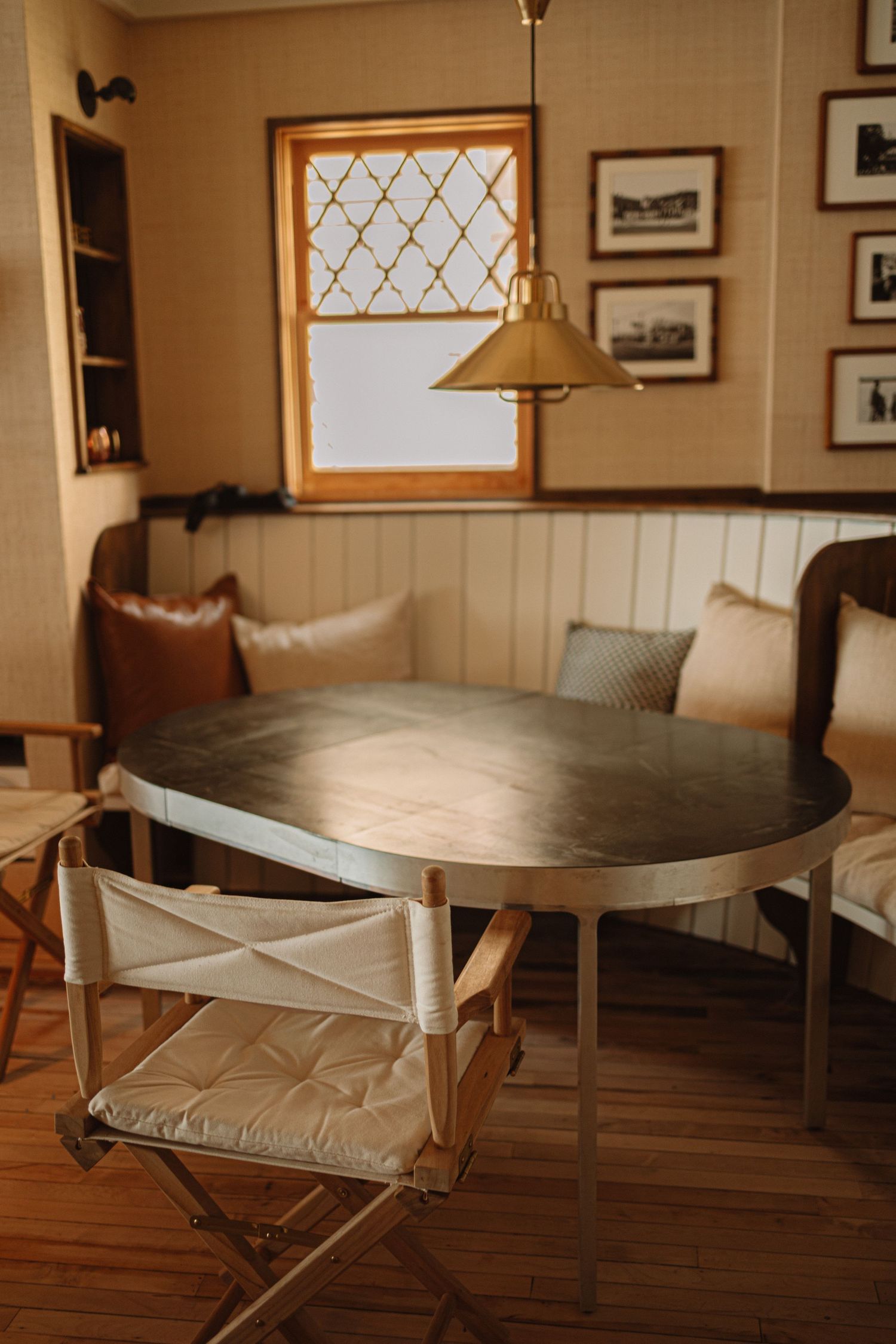 A modern farmhouse dining room with white wainscoting, wood floors and built-in bench seating in warm natural light.