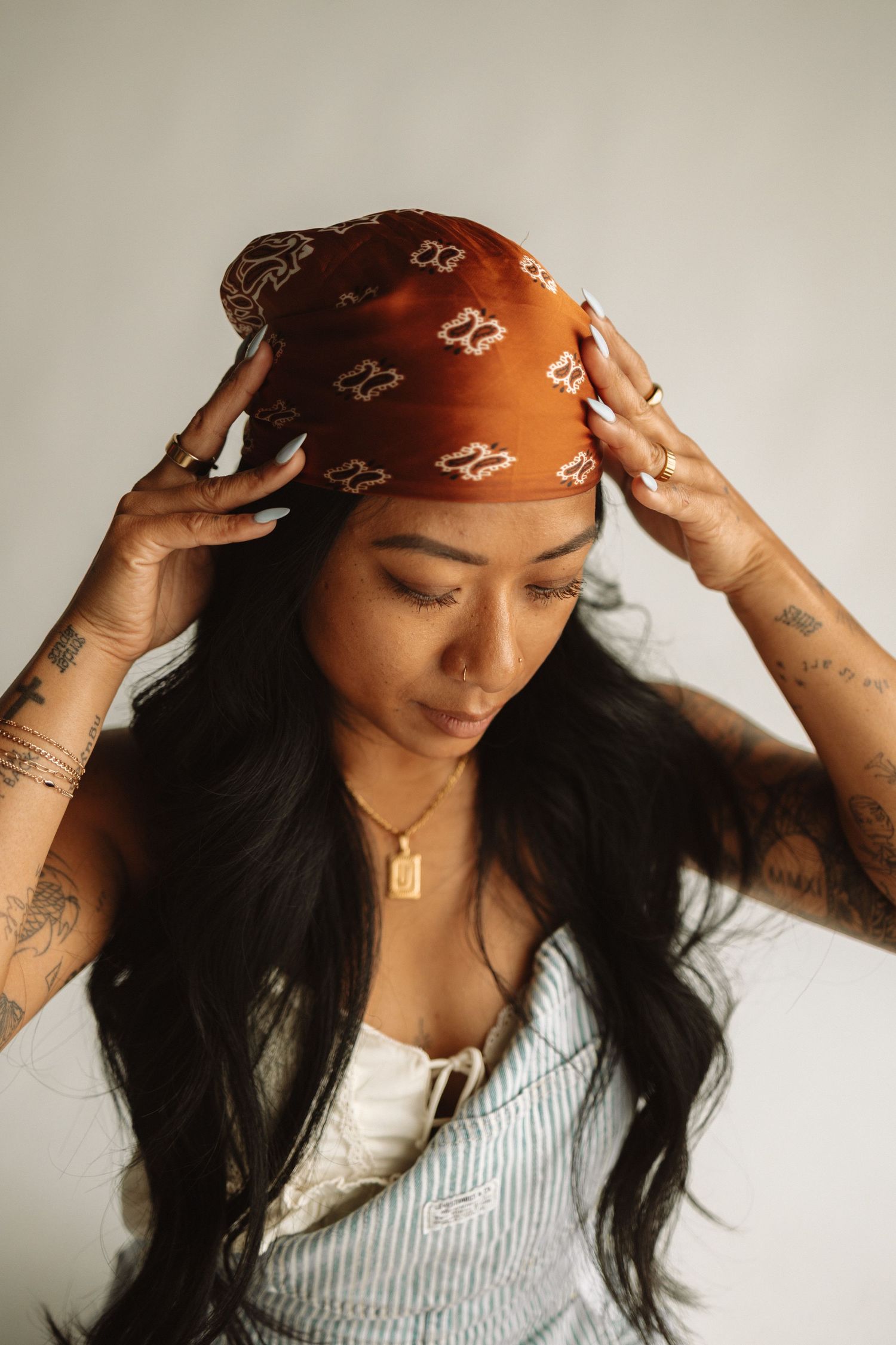 Multiple views of a person in a white top and red bandana adjusting their hair and headwear accessory.