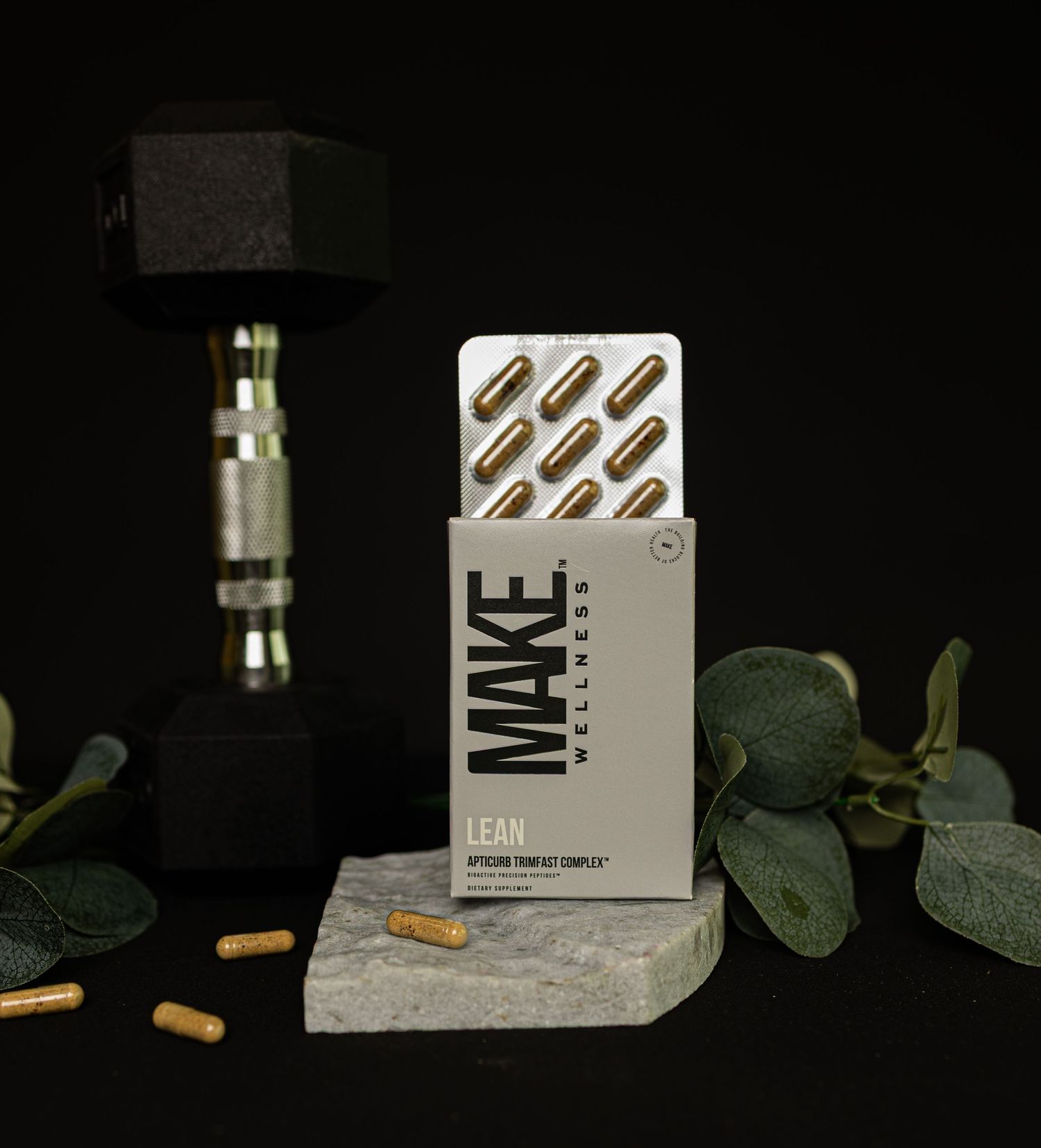 A vape cartridge and packaging displayed on concrete surface with eucalyptus leaves against dark background.