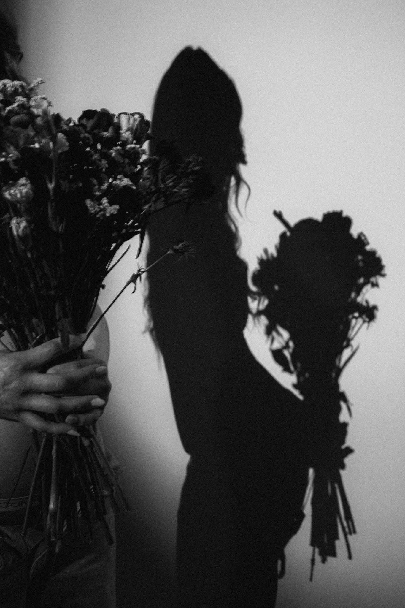 Silhouette series with person holding flowers against backlit background.