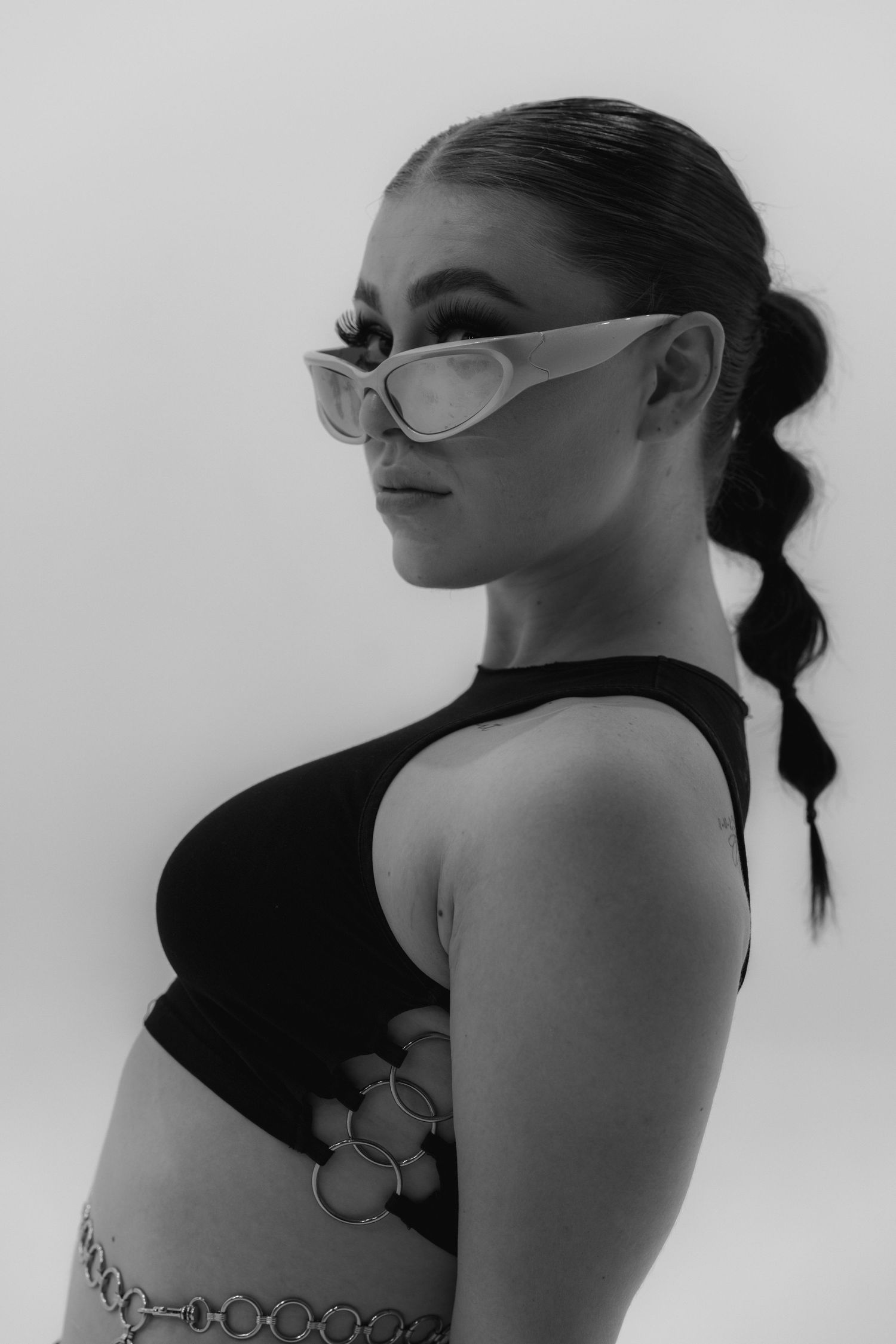 Artistic black and white fashion portrait featuring sleek sunglasses and a modern crop top design.
