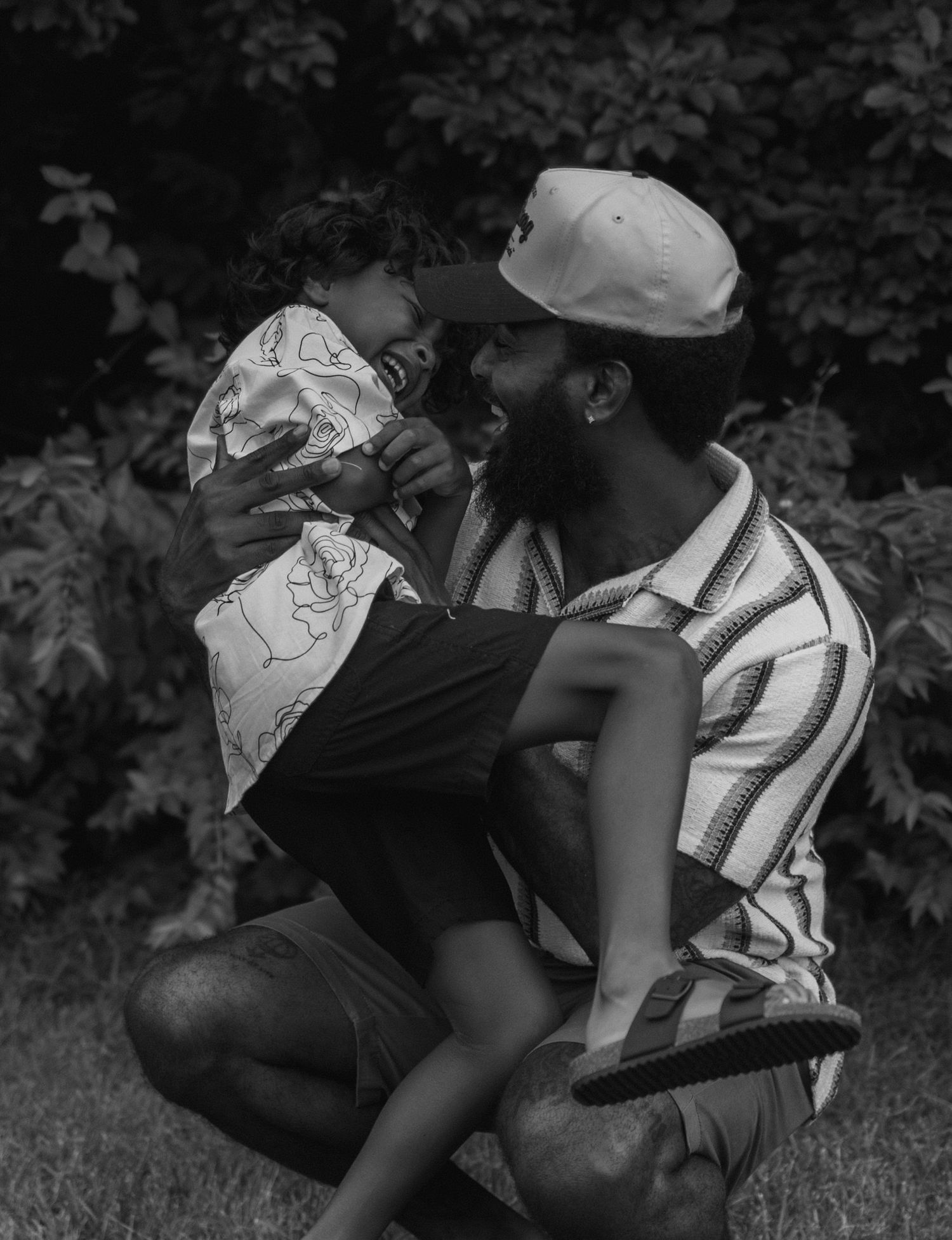 A couple in black and white sitting and reclining on the grass in an intimate moment at a park.