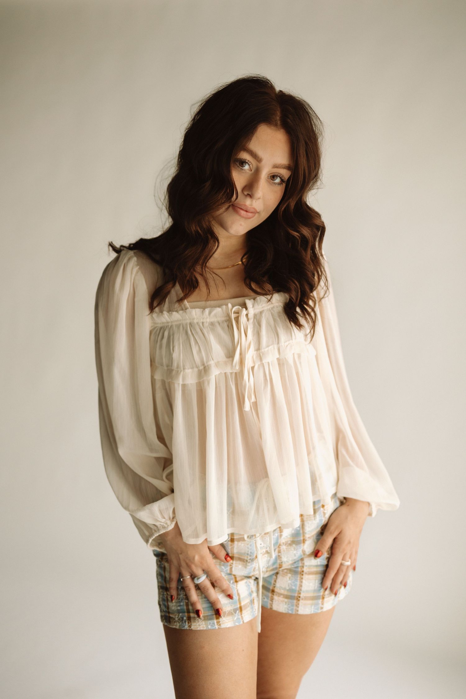 A series of fashion photos showing a white off-shoulder ruffle top paired with plaid shorts against a neutral background.