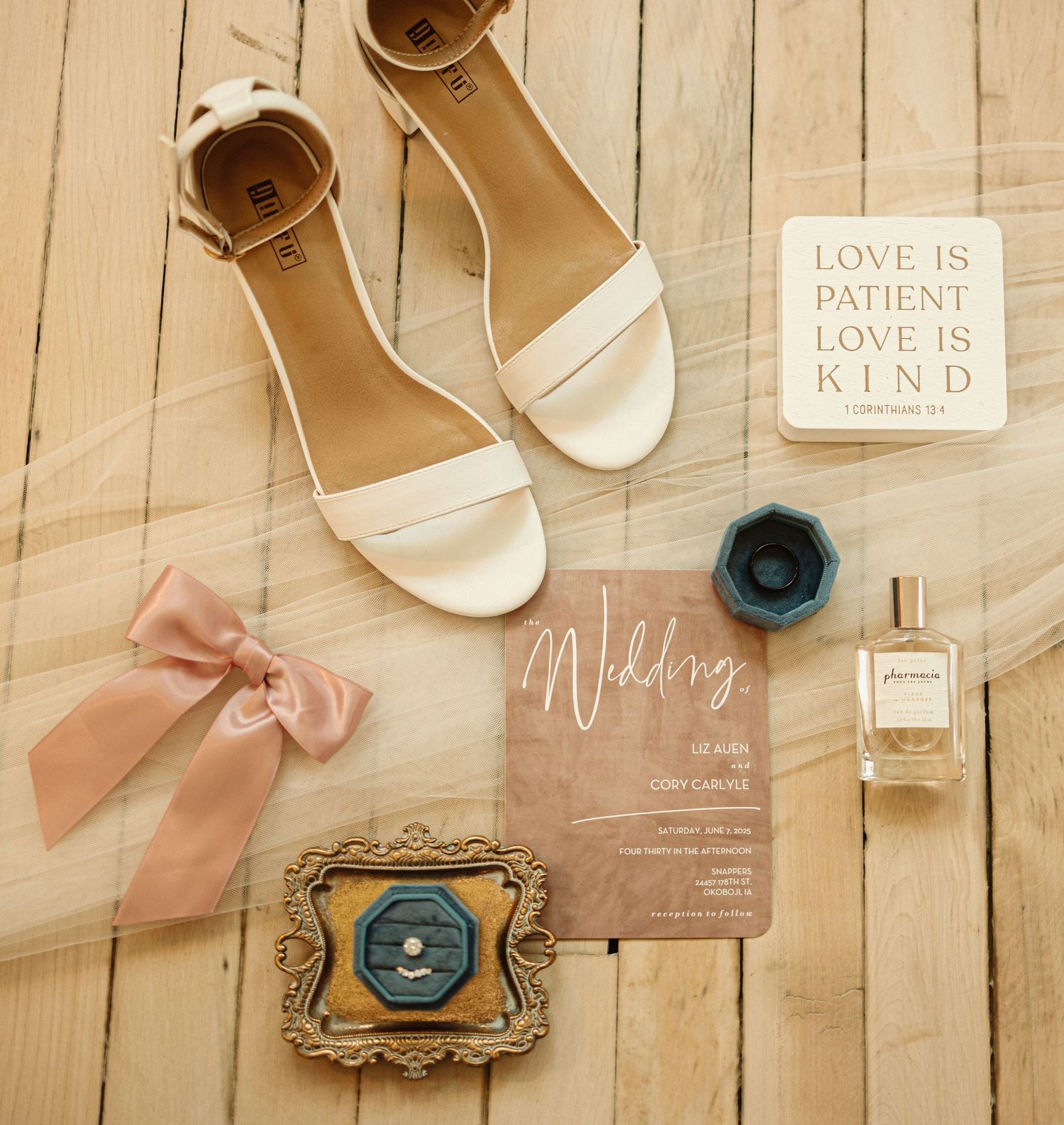 Elegant wedding flat lay with beige heels, pink bow, vintage keys and ornate frames on wooden background.