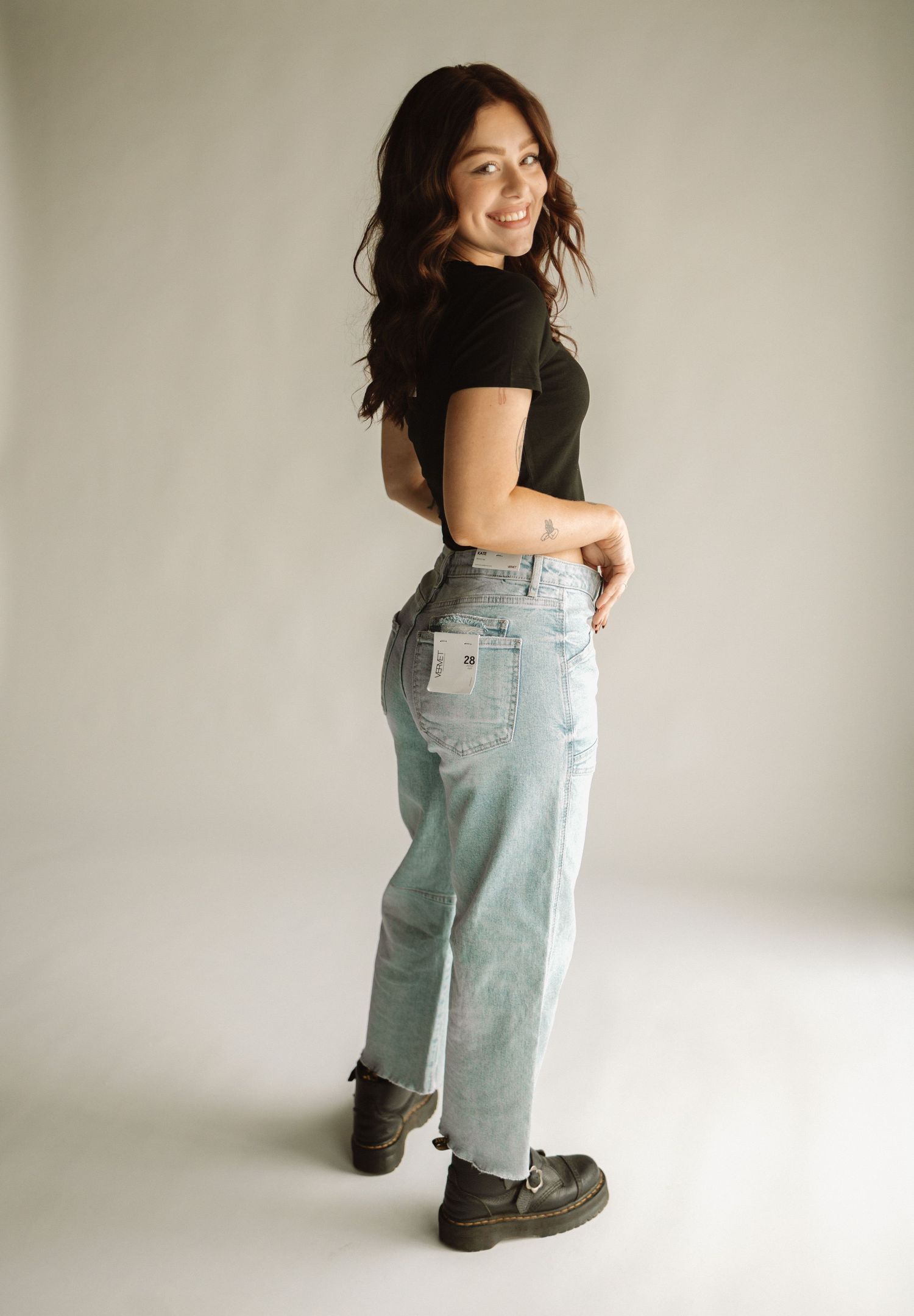 A series of photos showing a person in black top and light blue jeans demonstrating clothing movement and fit details.