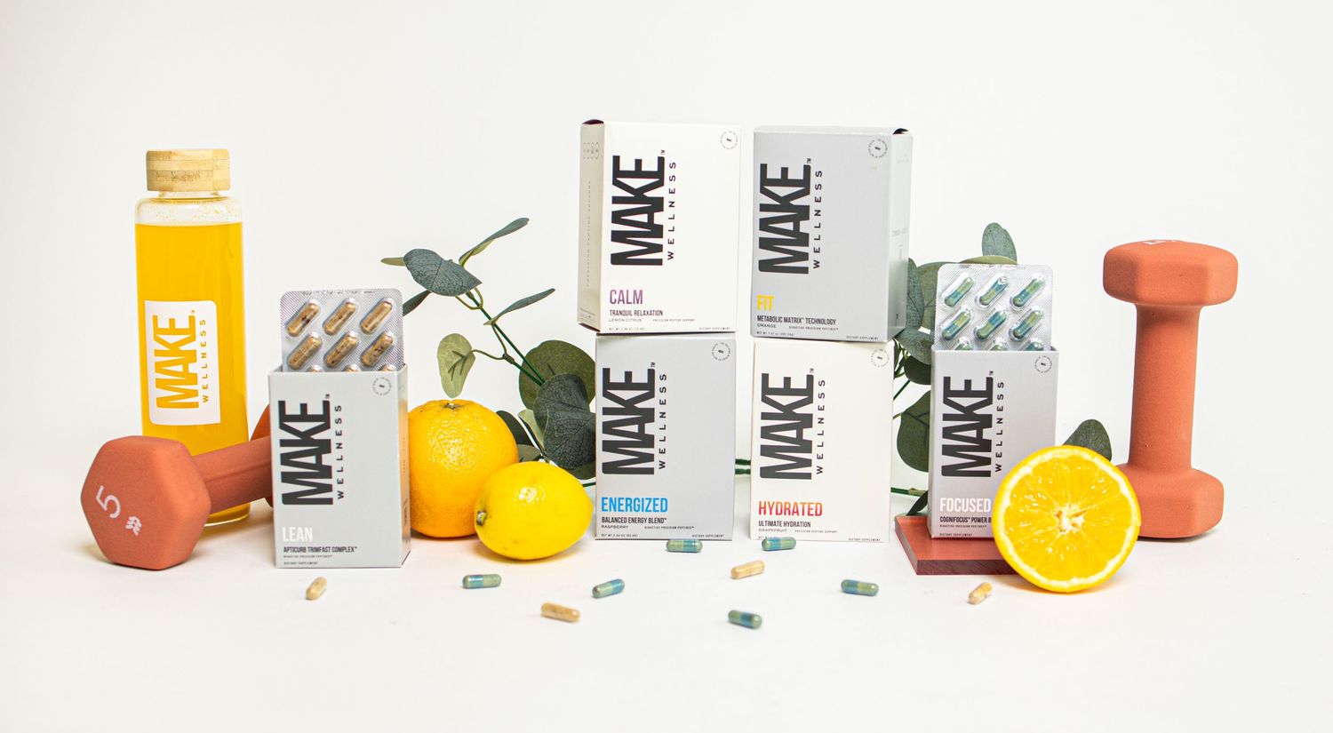 Fitness and wellness products including supplements, citrus fruits, and orange dumbbells arranged in a clean minimalist display.