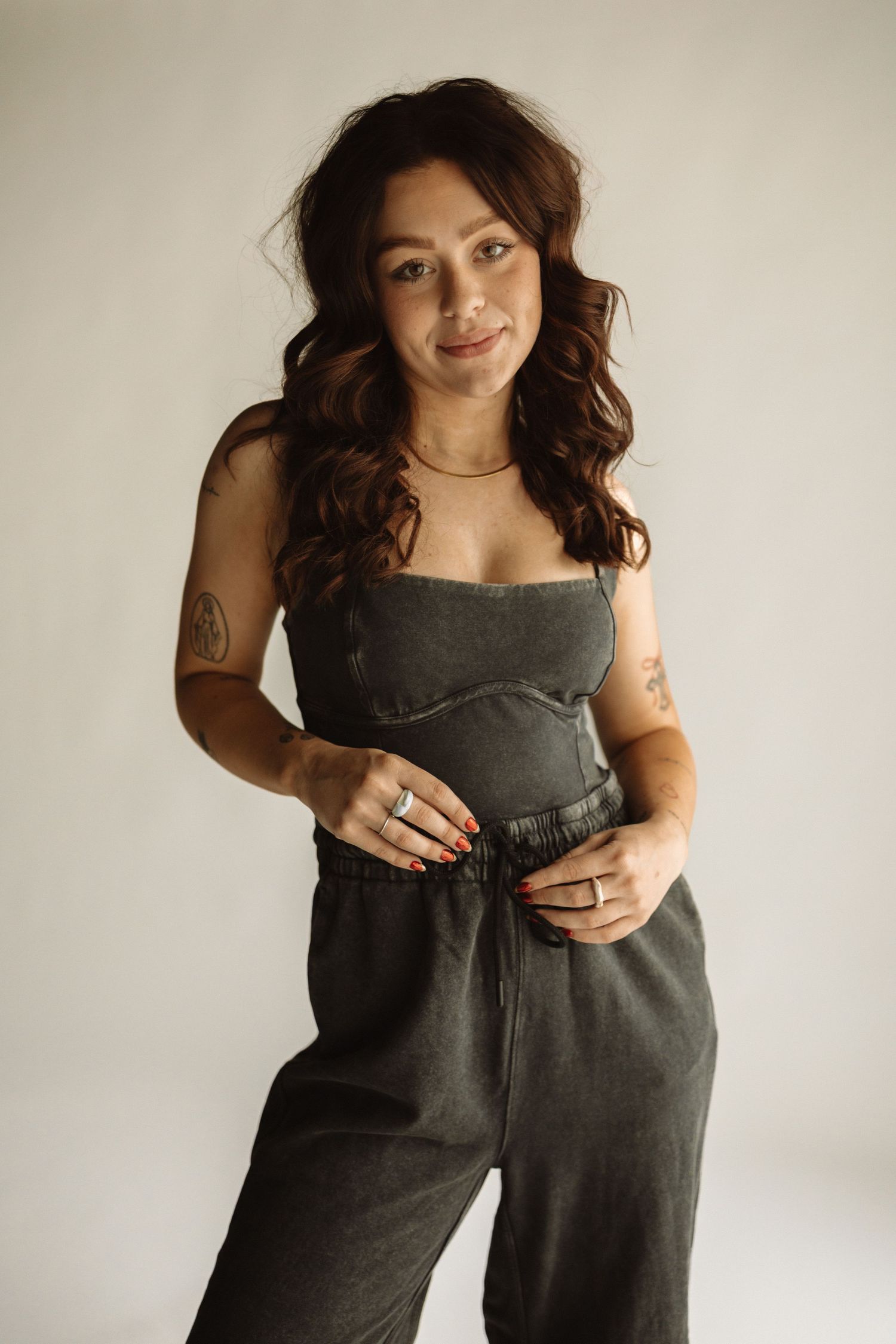 A sequence of fashion photos showing someone wearing a gray jumpsuit against a light neutral background.