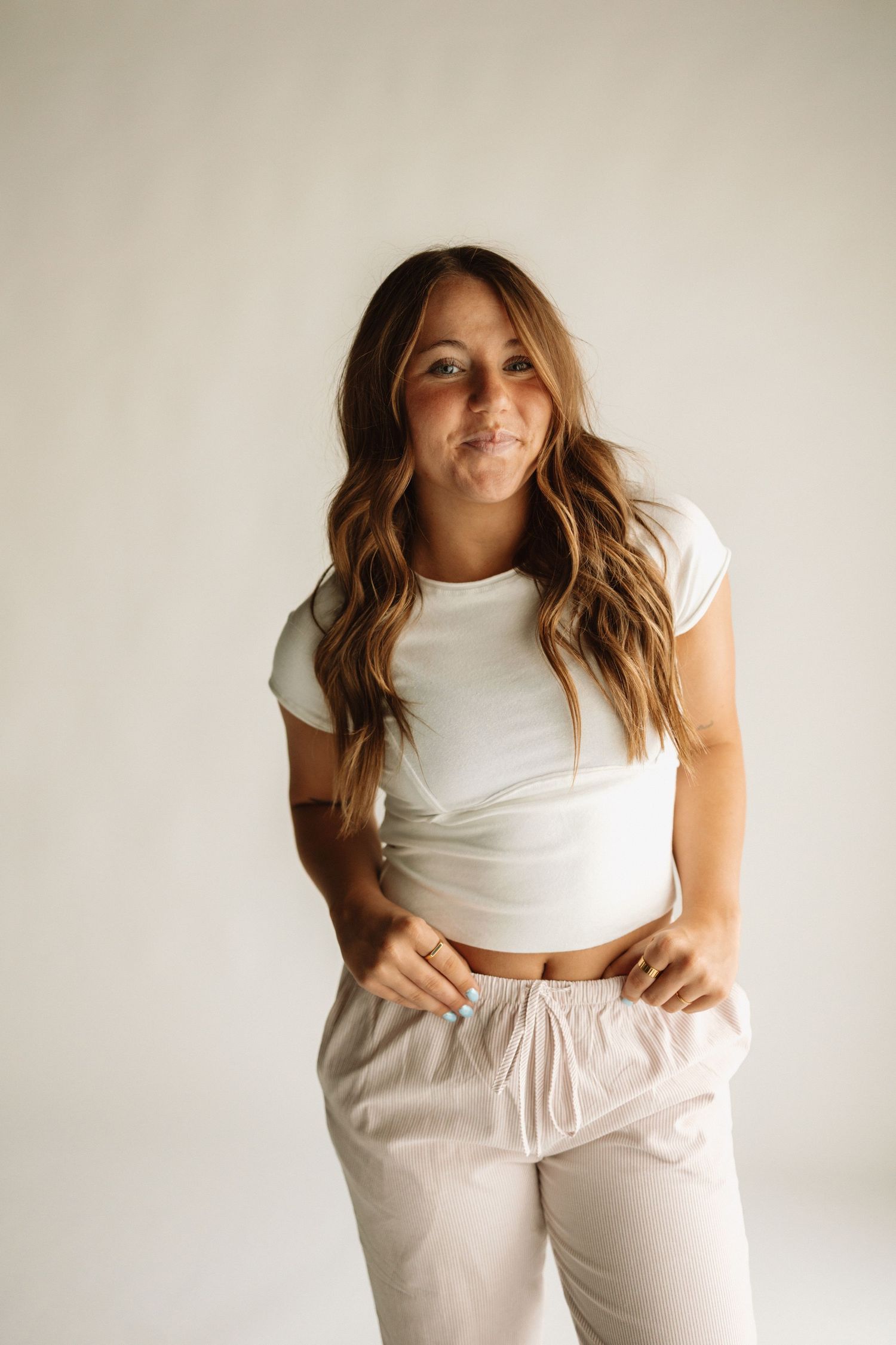Four lifestyle shots of someone modeling a white crop top and light beige sweatpants against a neutral background.