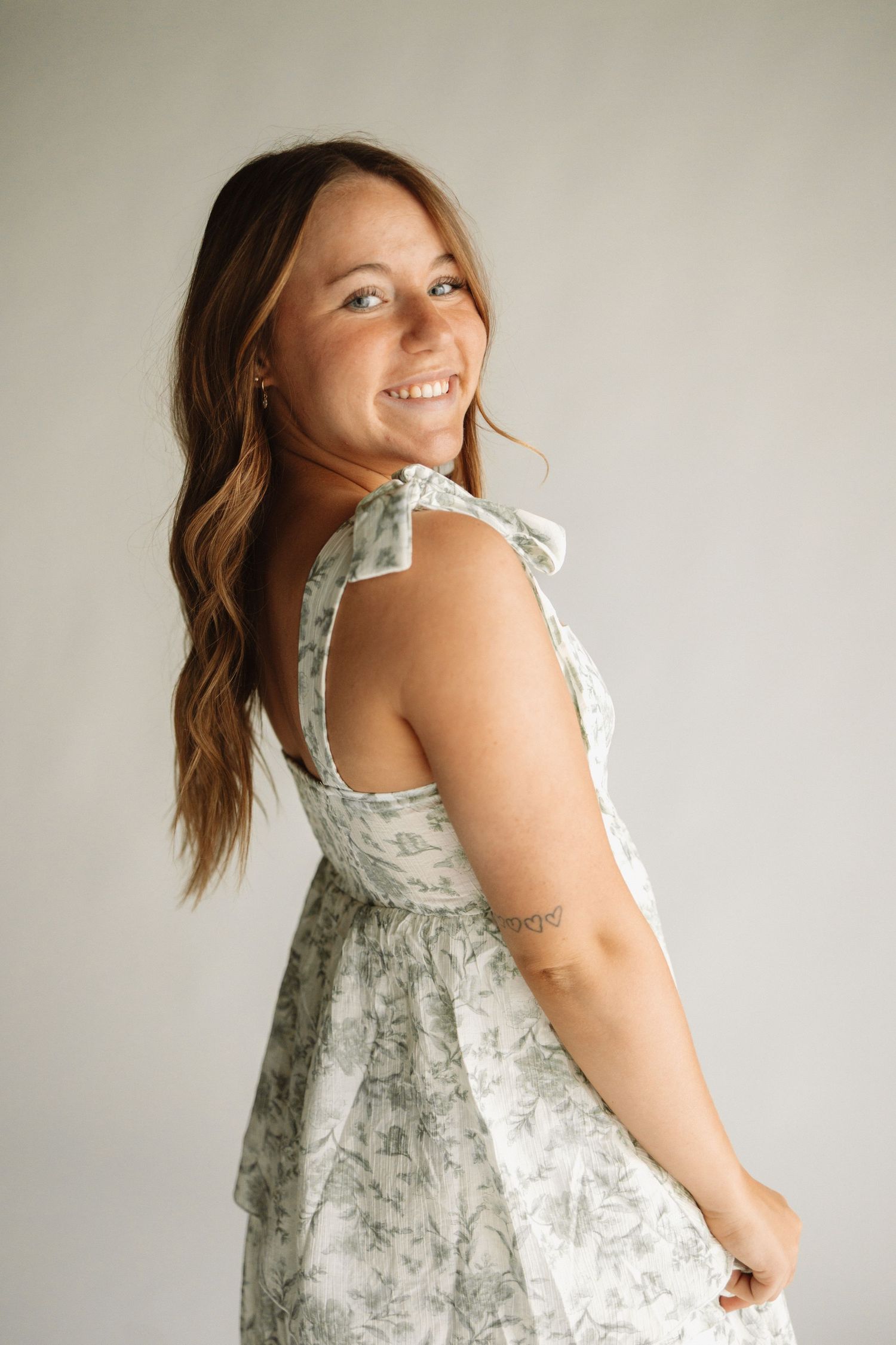 Side view of a floral cottage core style dress with tie straps and a fitted bodice against a neutral background.