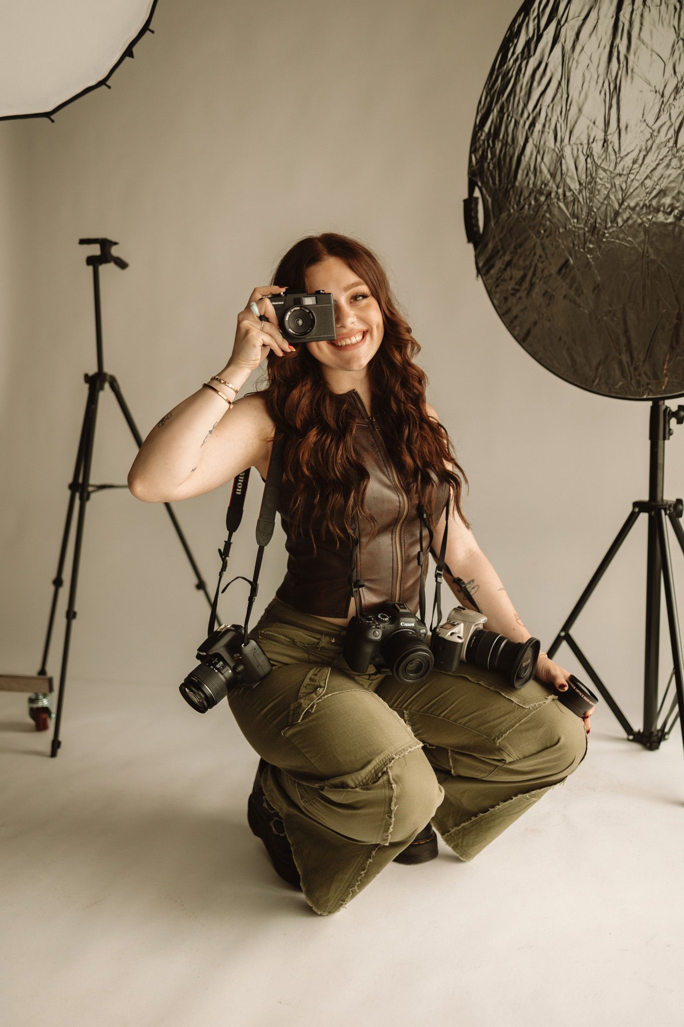 Photographer in studio setting with professional lighting equipment and multiple cameras.