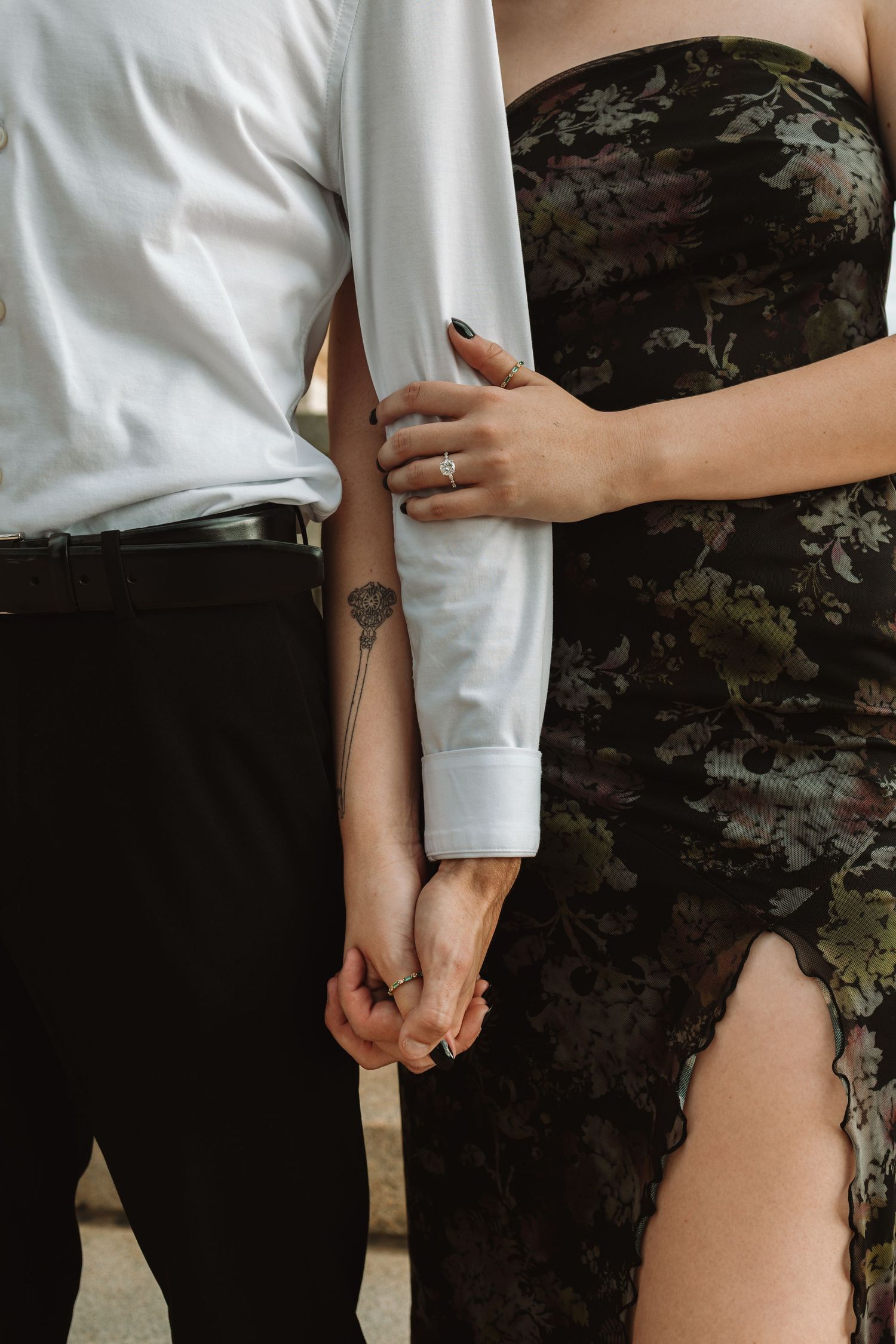 Close-up view of hands holding white fabric against a dark floral dress, creating an intimate contrast.