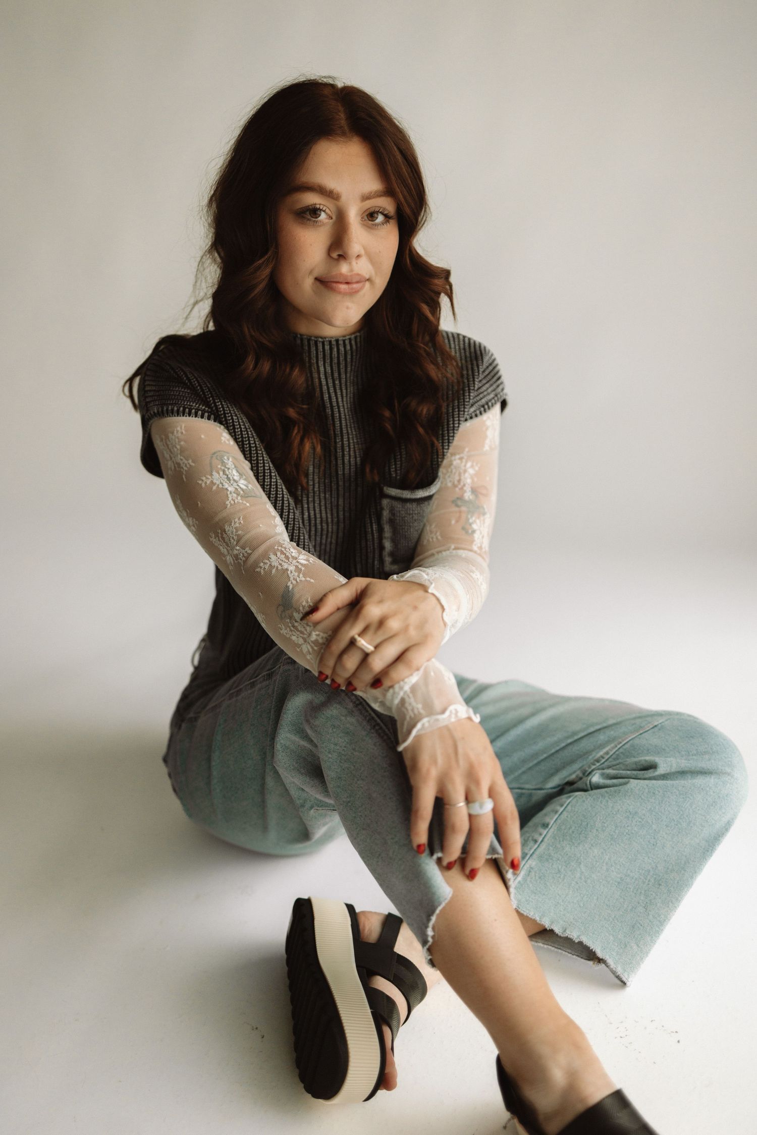 Fashion portrait series of a person in turtleneck sweater and light jeans posing against white background.