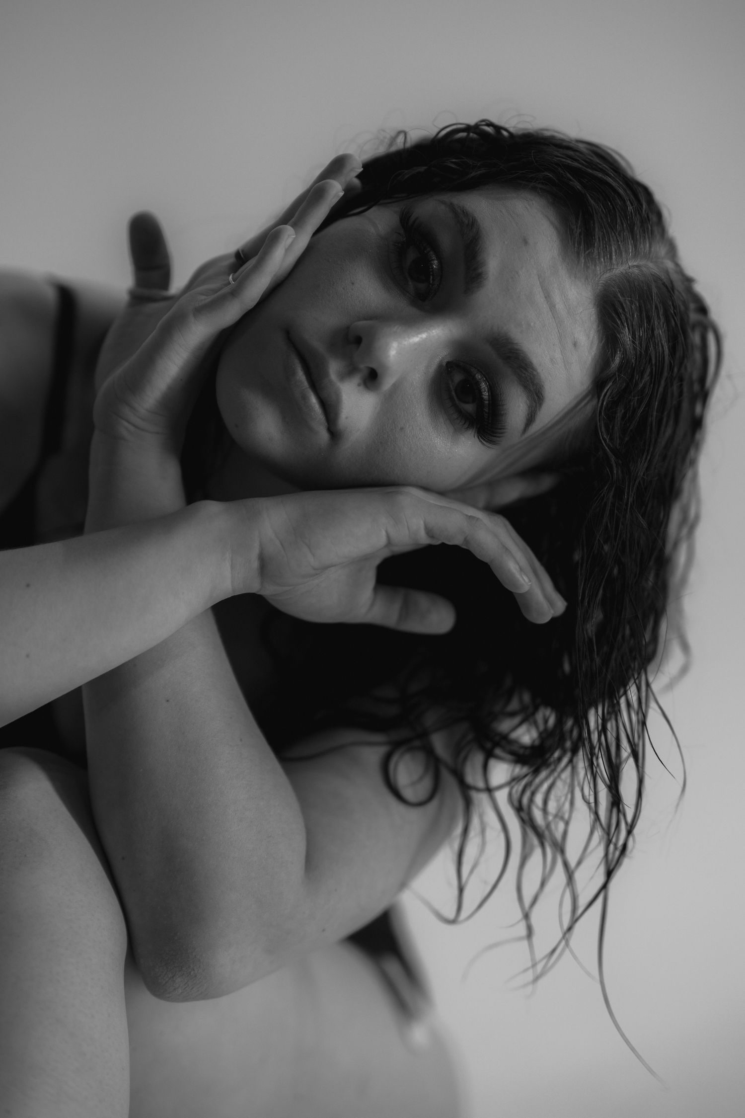 Artistic black and white portrait series showing dramatic poses with wet hair against light background.