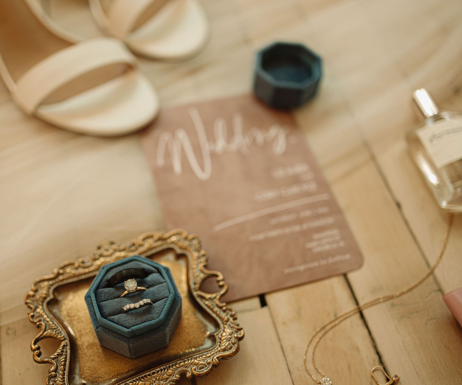 Vintage buttons and antique gold frames arranged on a tan paper surface with elegant script writing in the background.