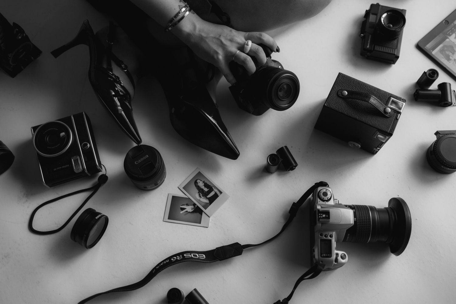 A flatlay collection of vintage and modern cameras arranged on a dark surface.