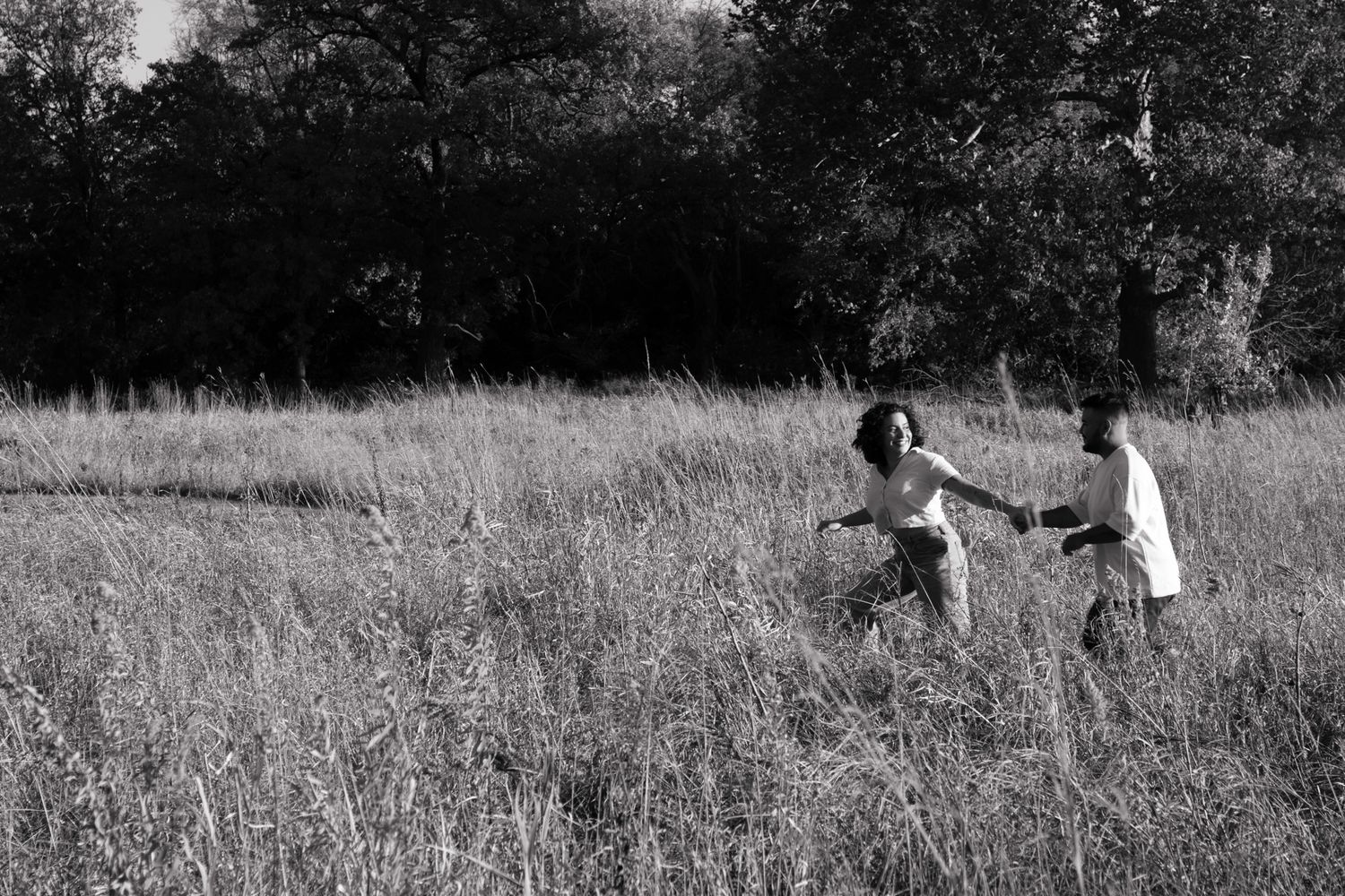 Two people playing and running together in a sunlit meadow.