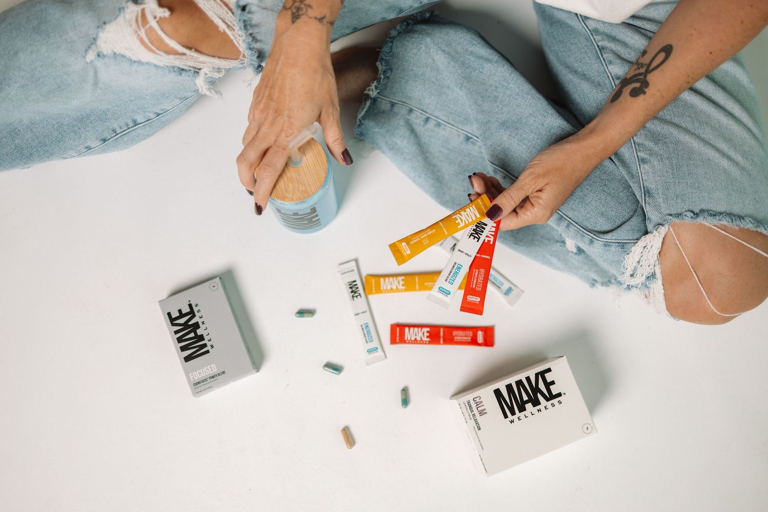 Hands using art supplies and stickers to create a colorful craft project on a white surface.