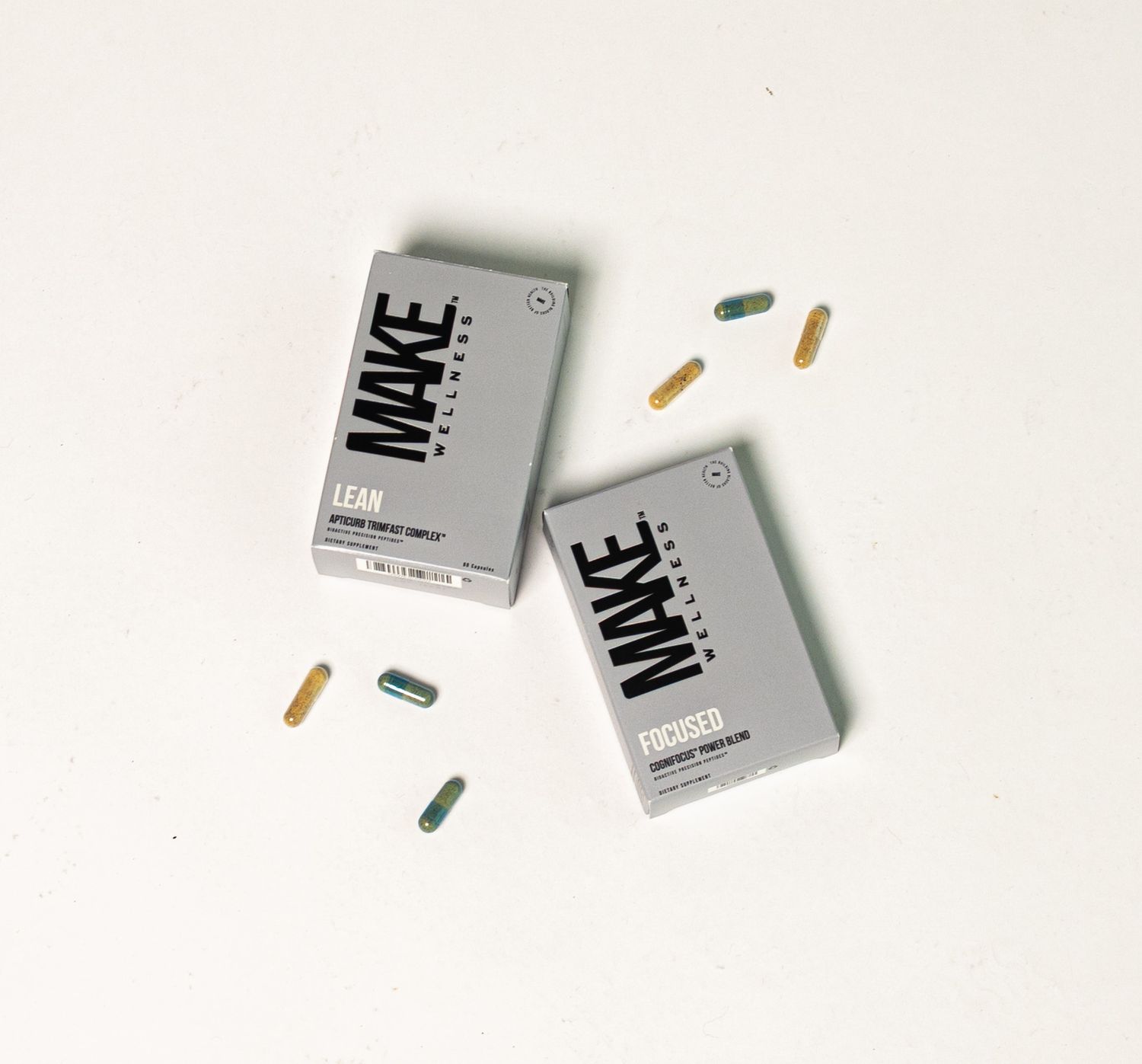 Small silver and white pill boxes and scattered capsules arranged on a white background.