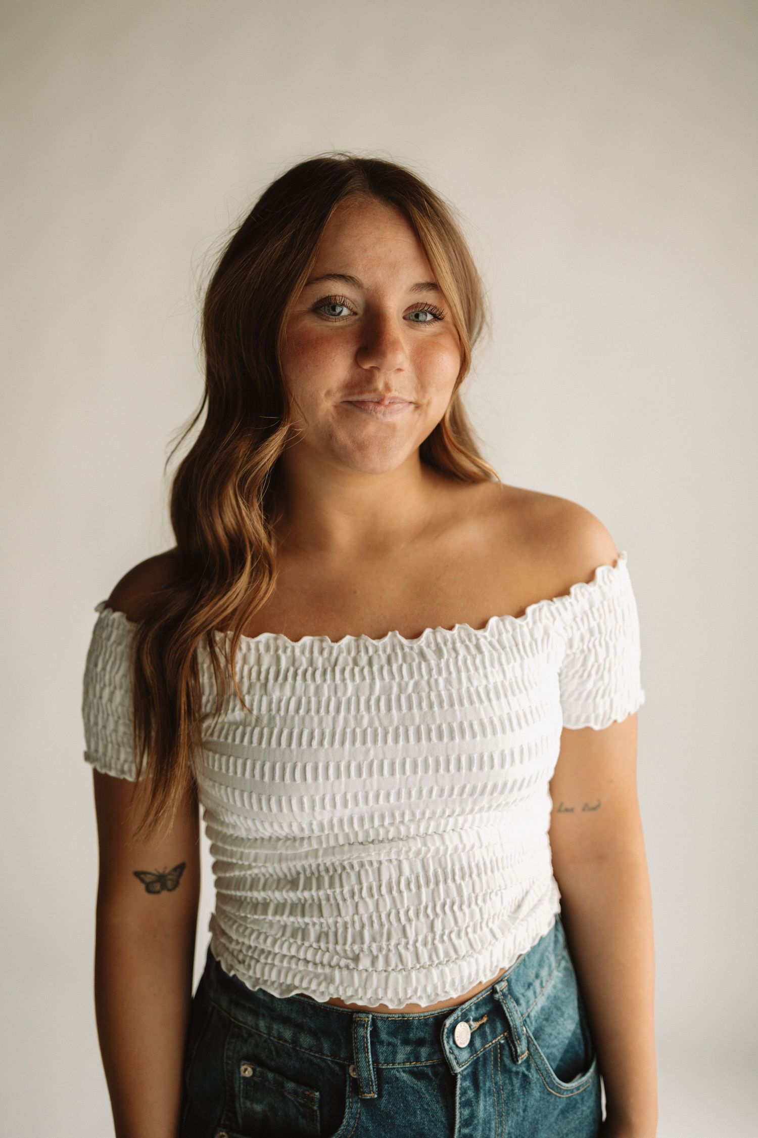 A progression of fashion photos showing a white smocked off-shoulder crop top paired with blue denim jeans against a light backdrop.