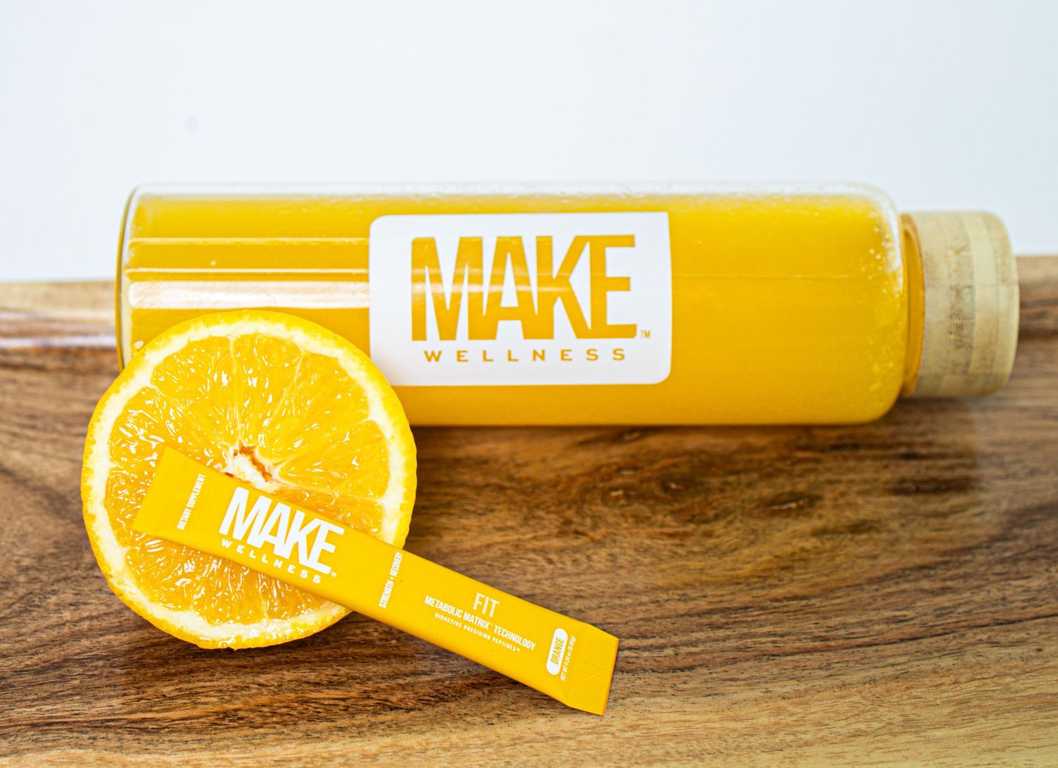 Bright yellow lip balm tubes with orange citrus slices on wooden surface display fresh and vibrant packaging design.