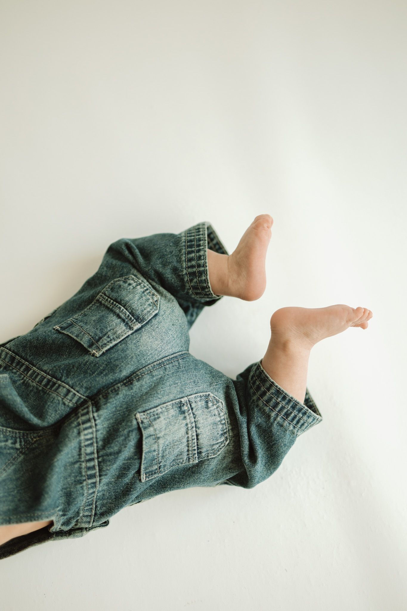 A series of five artistic photos showing a denim jacket sleeve with a bare foot poking through against a white background.