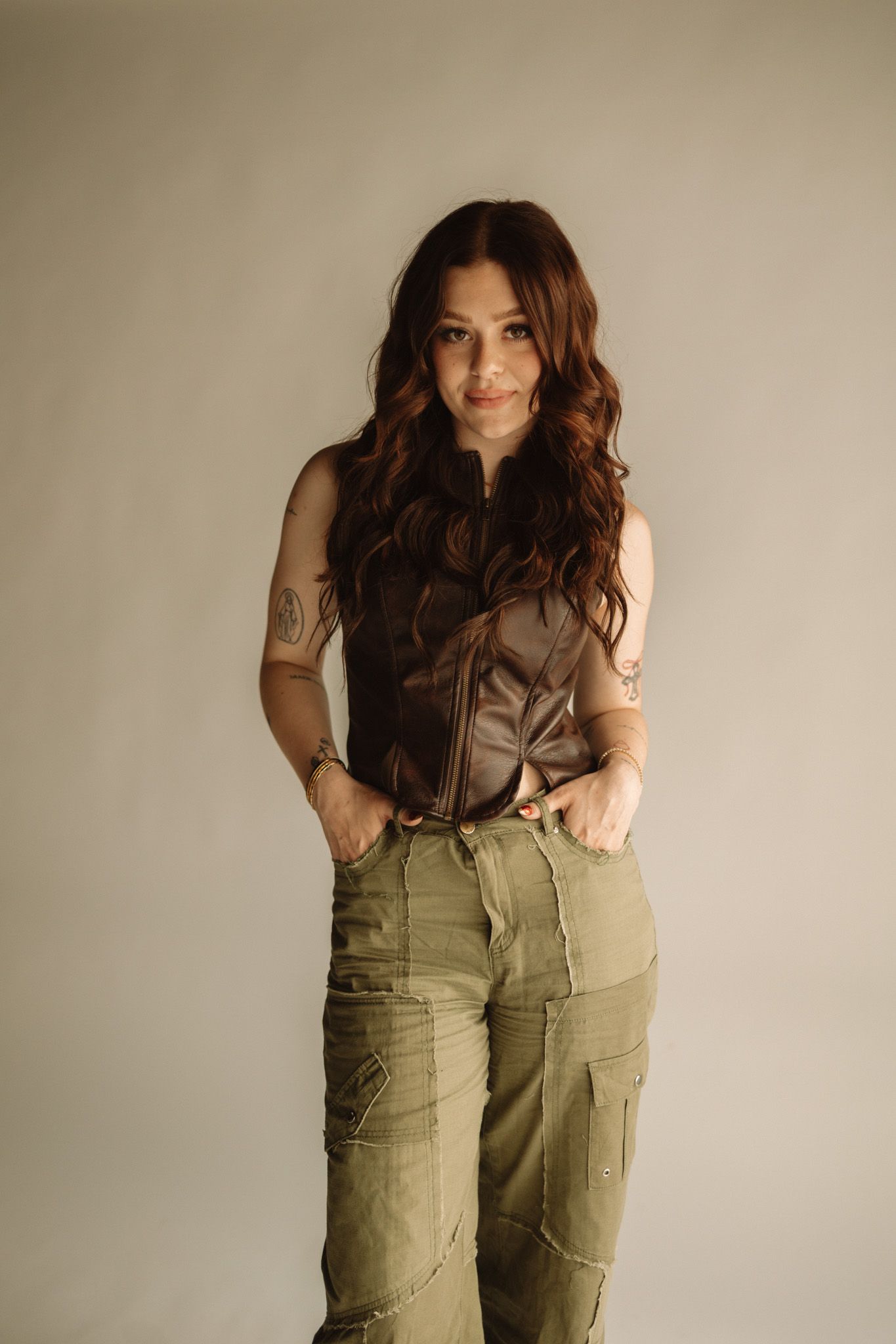 A fashion photo series showing someone posing in olive cargo pants and a dark top against a neutral backdrop.