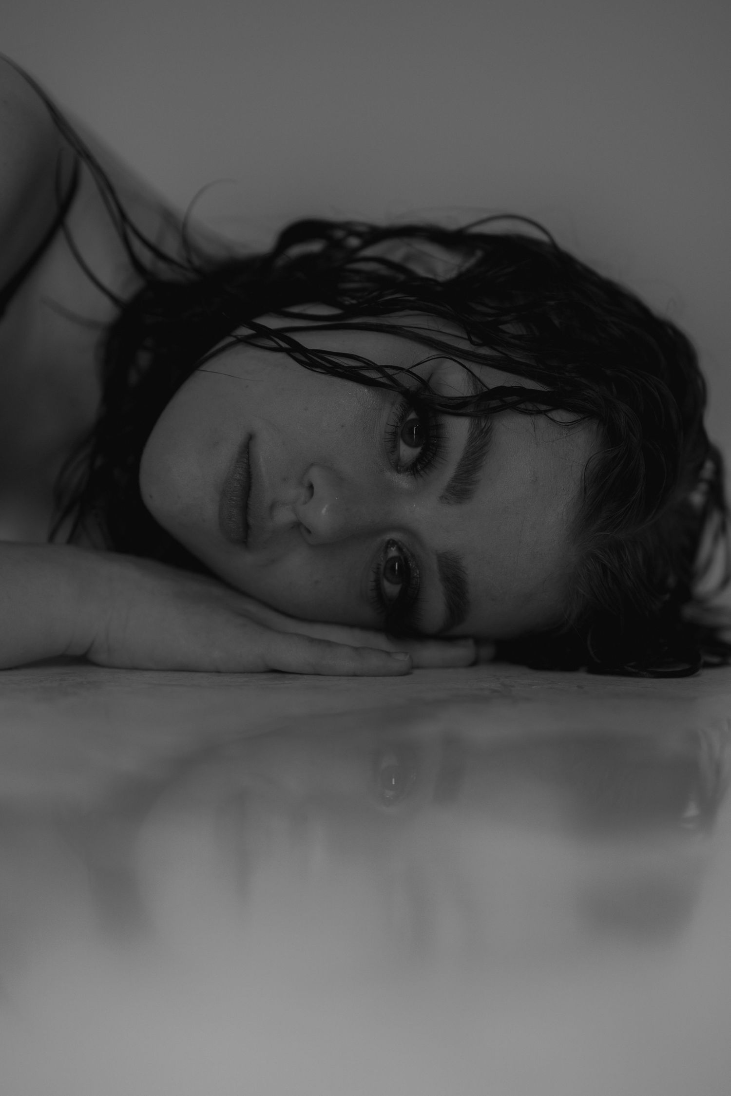 Black and white closeup portraits of figure lying down with dramatic shadows and wet hair.