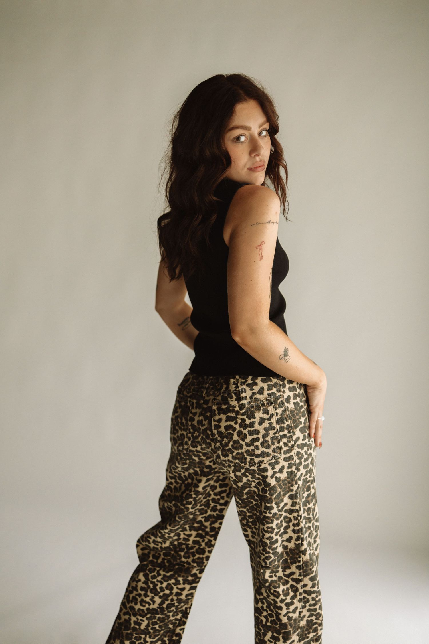 Woman poses in animal print jumpsuit against white background showing different angles and poses.