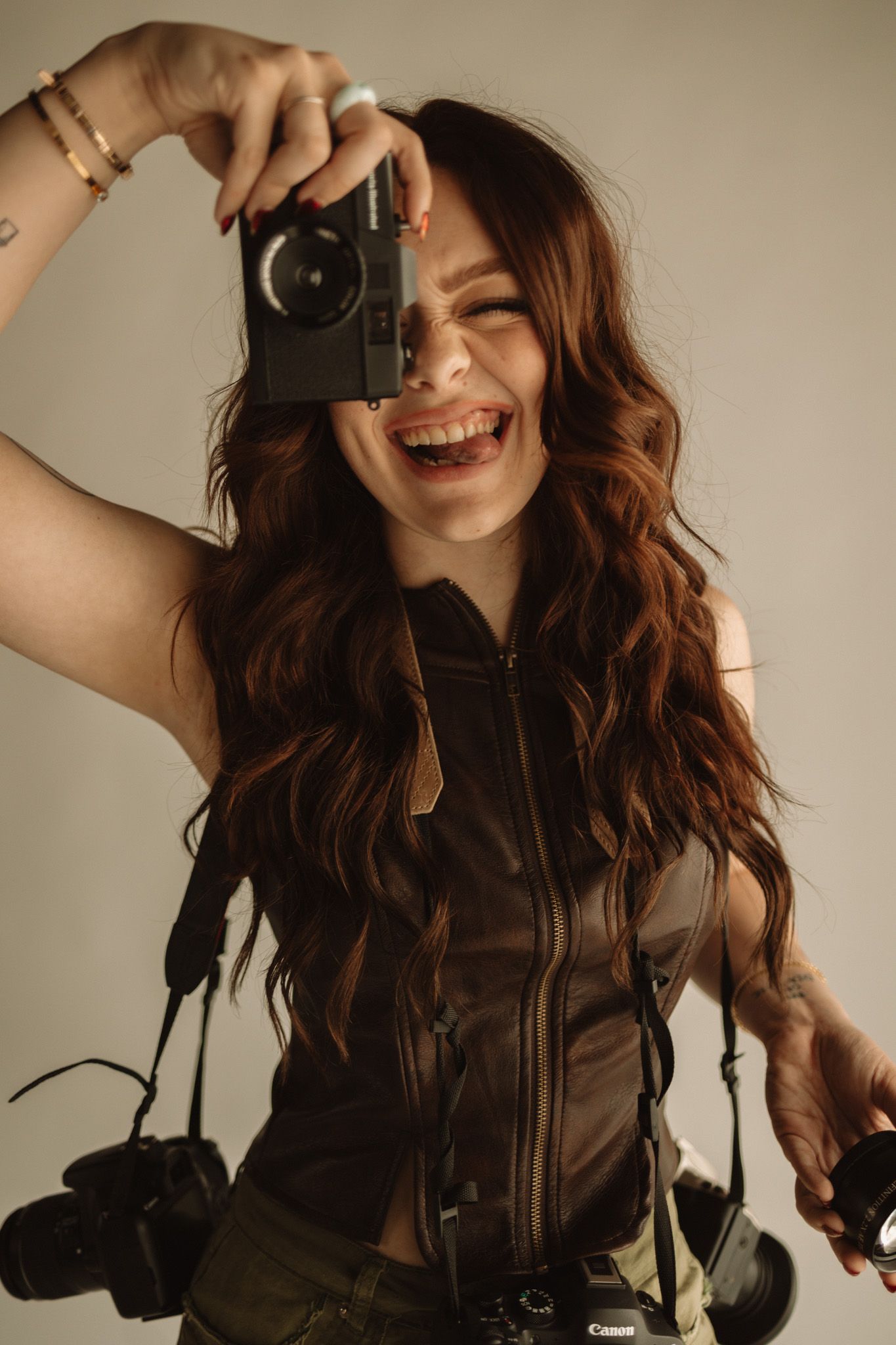 A photographer holding a vintage camera smiling and posing in various playful shots against a neutral background.