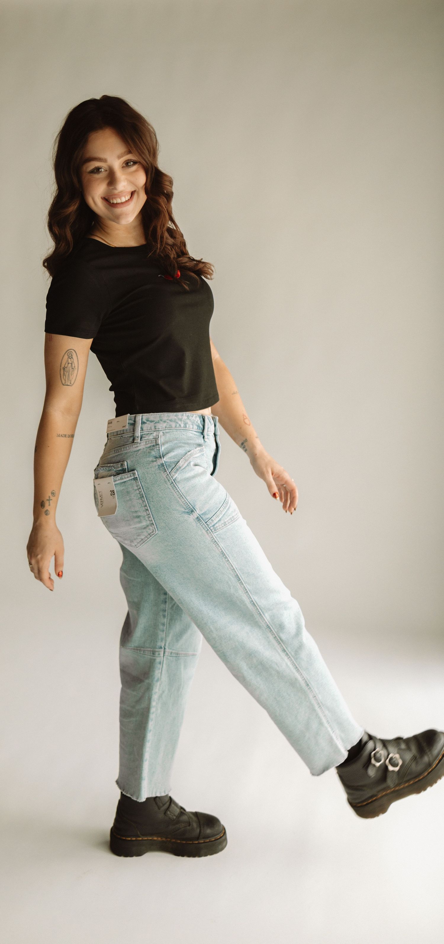 A series of motion shots showing someone playfully posing in light blue jeans and black boots against a white background.