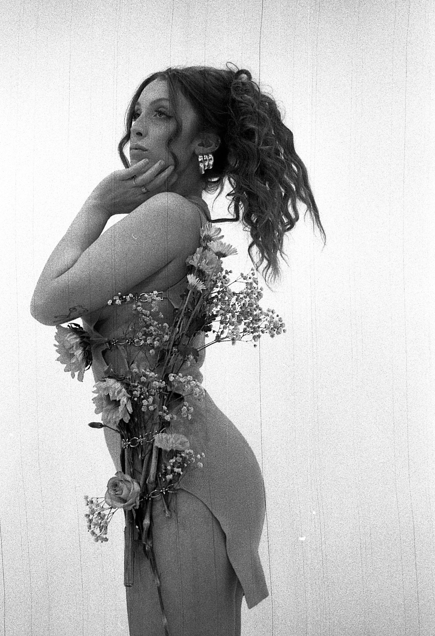 Delicate black and white artistic nude figure study with flowers creating ethereal double exposure effects.