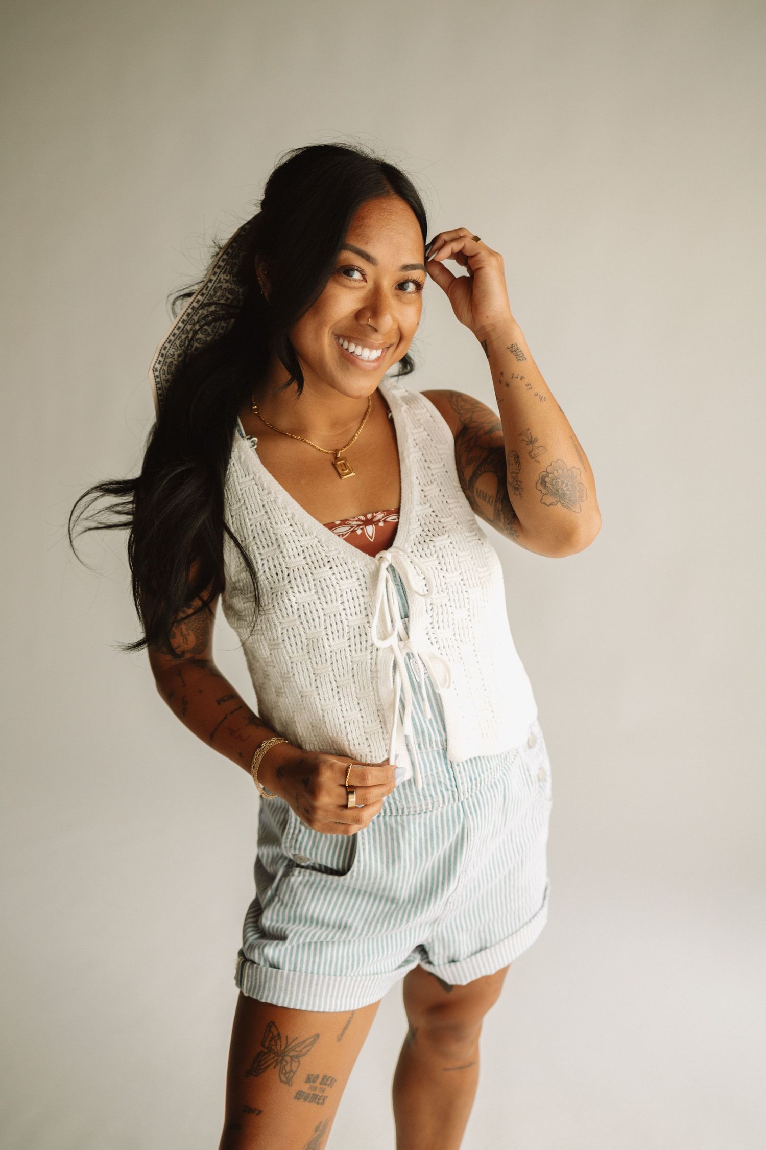 Someone in a white crochet top and light blue striped shorts poses casually against a neutral background.