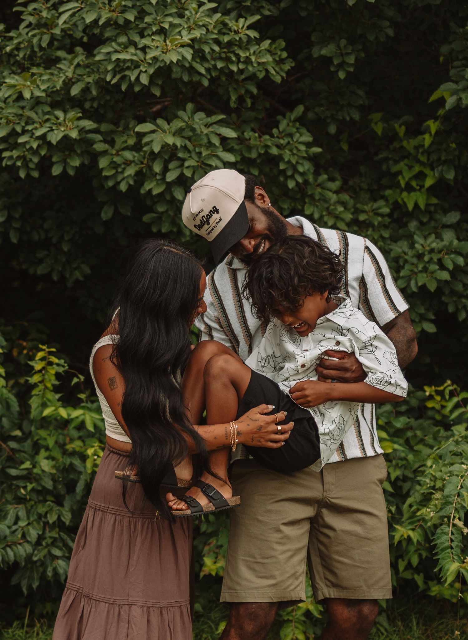 A couple shares tender moments outside in a series of intimate poses against a backdrop of green foliage.