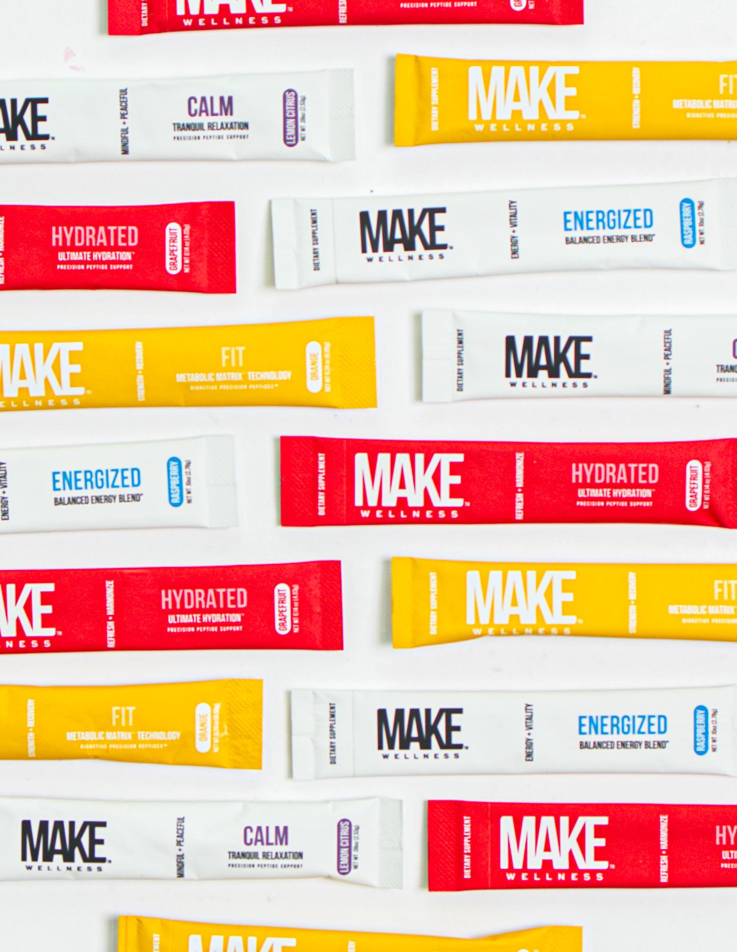 Colorful array of MAKE supplement packets displayed in red, yellow, and white packaging with different formulations.