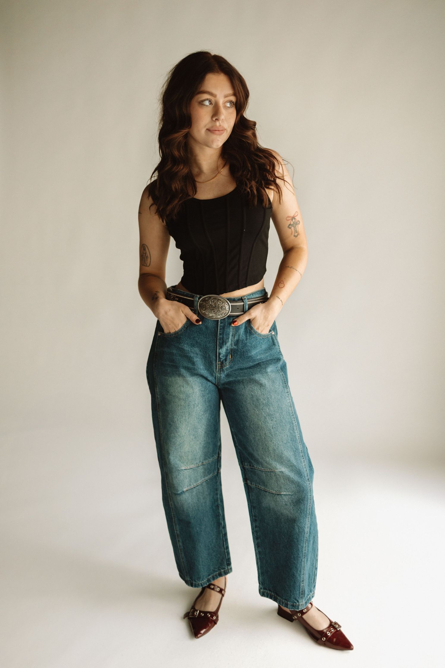 A sequence of fashion poses showing styling of loose-fit vintage denim jeans paired with a black top and brown shoes.