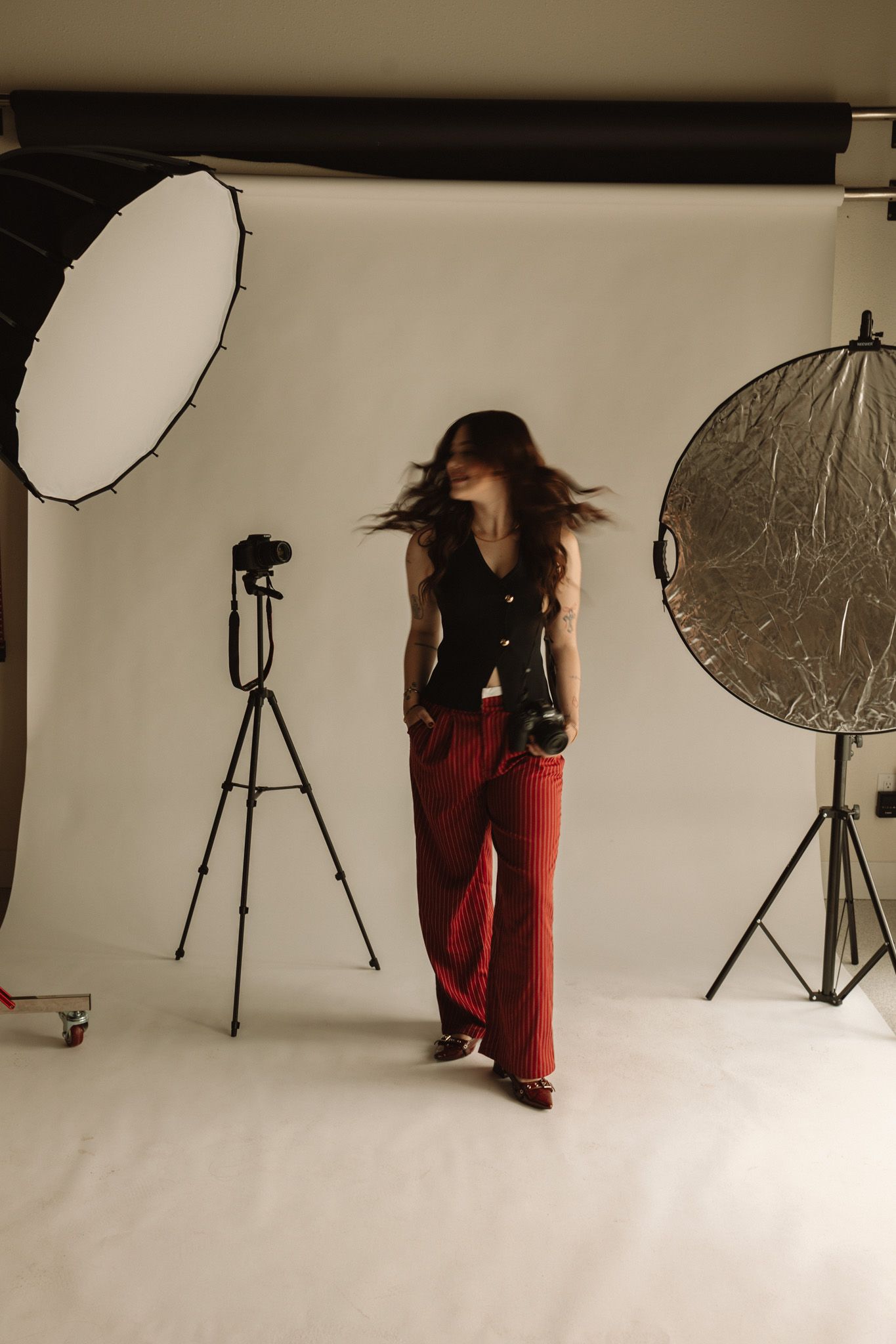 A photo studio setup shows lighting equipment and a figure moving through a white cyclorama background.