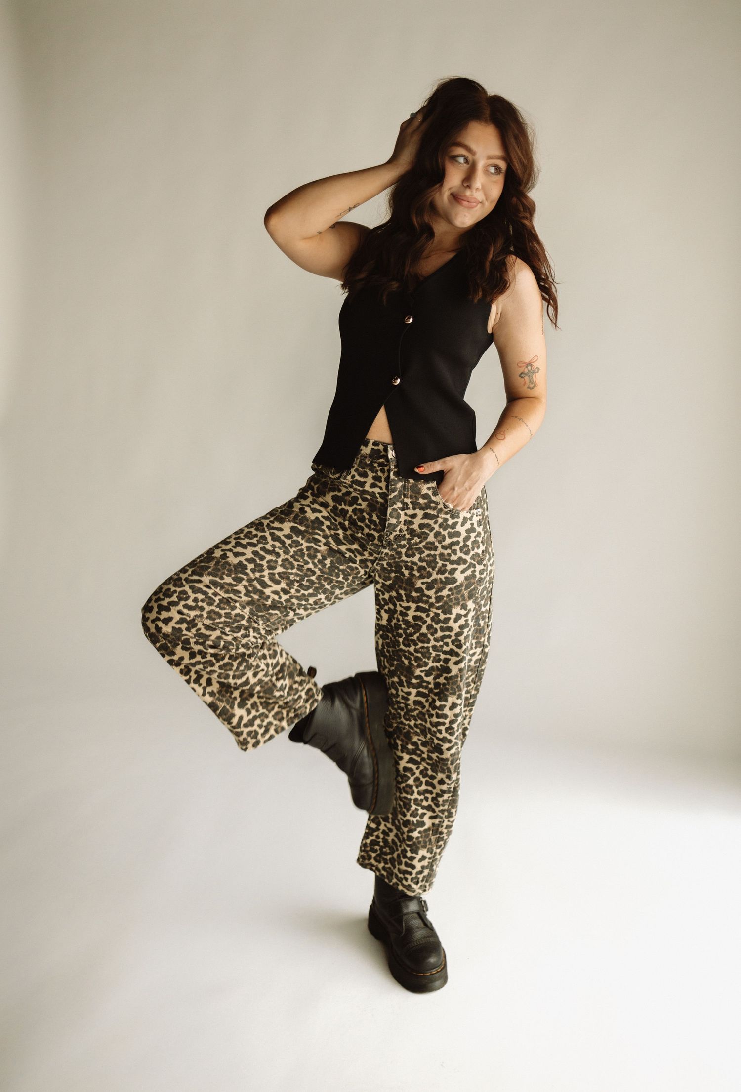 Model wearing black top and leopard print pants poses in various dynamic stances against white studio backdrop.