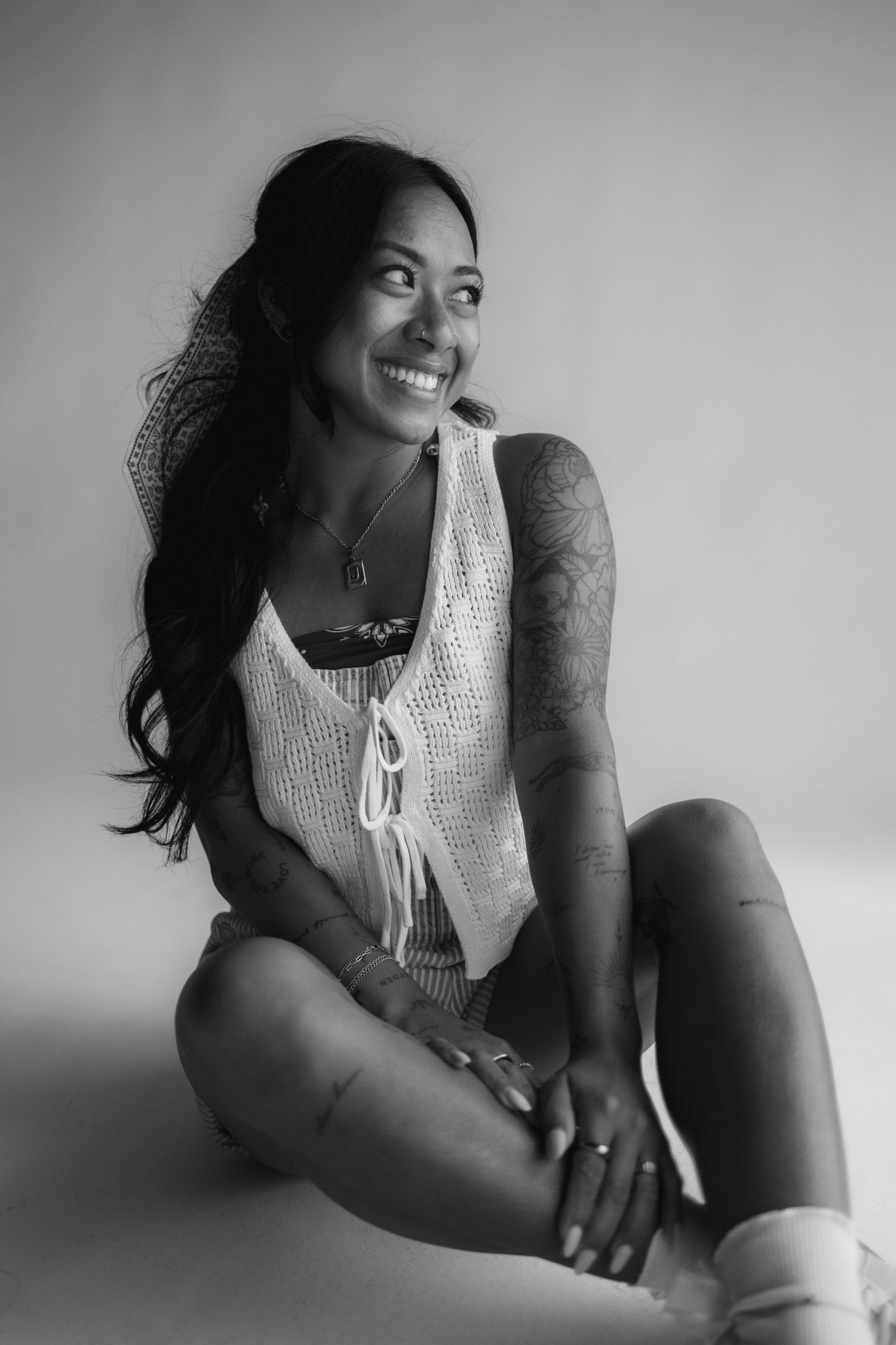 Black and white photo series showing someone in a white knit top posing expressively while sitting against a light background.