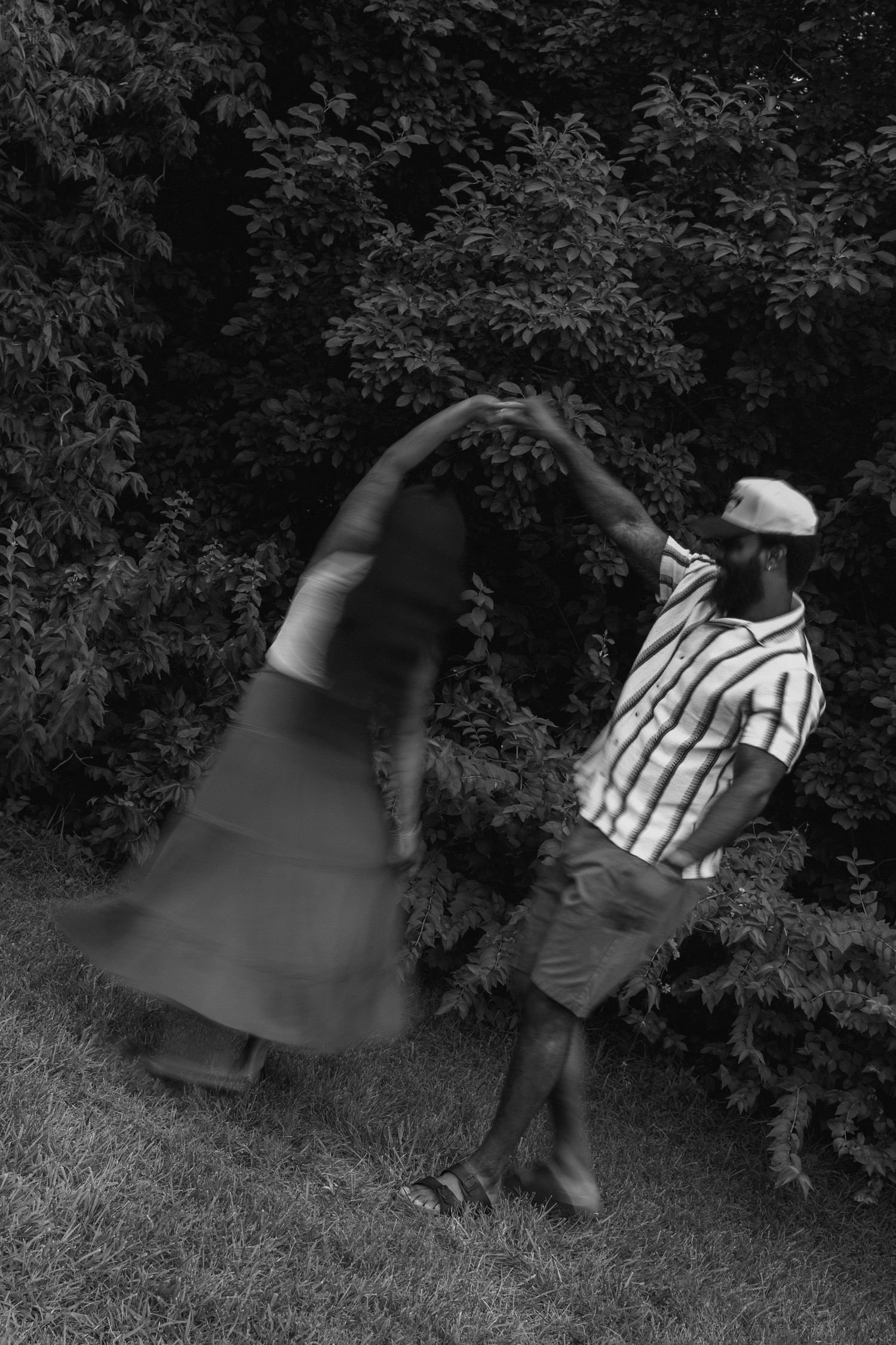 Black and white motion blur sequence showing person falling down on grass near bushes in multiple frames.