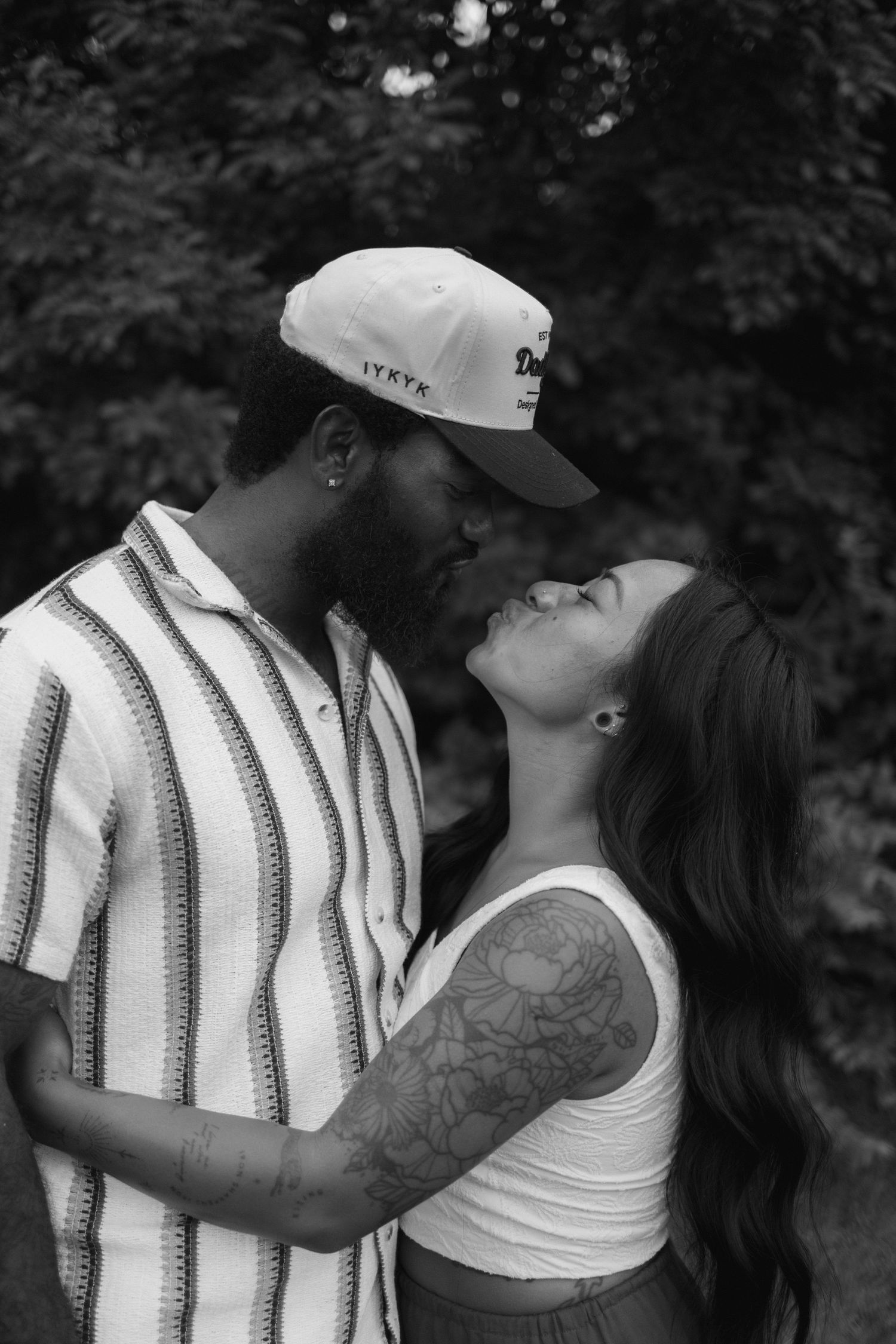 A romantic black and white photo series showing a couple embracing and sharing intimate moments outdoors.