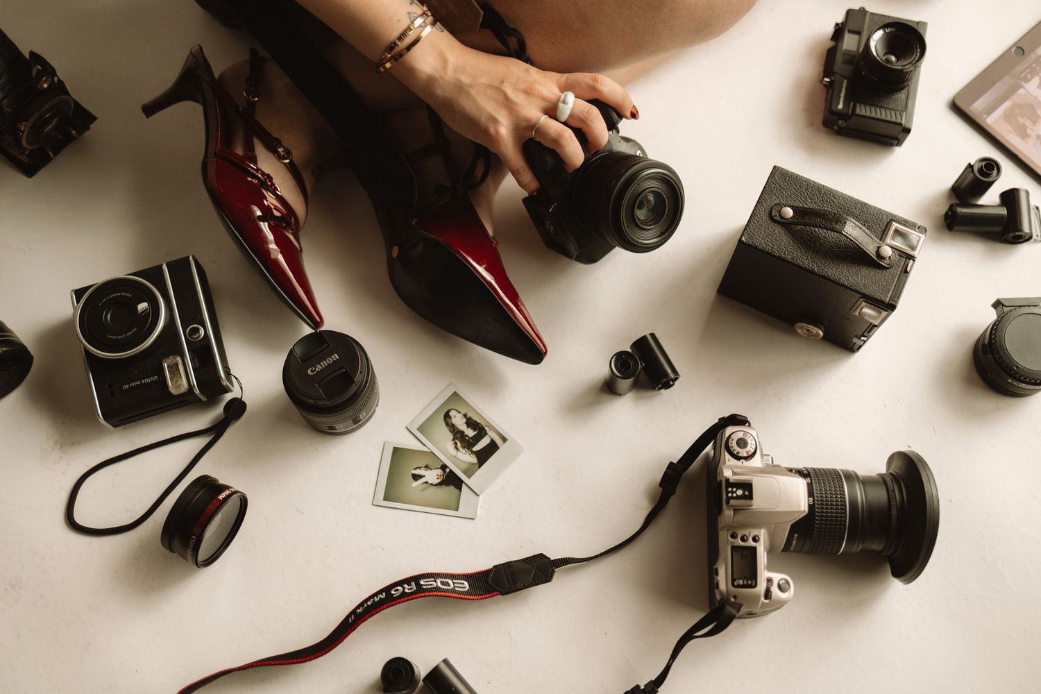 Overhead view of vintage cameras and photography equipment with red shoes.