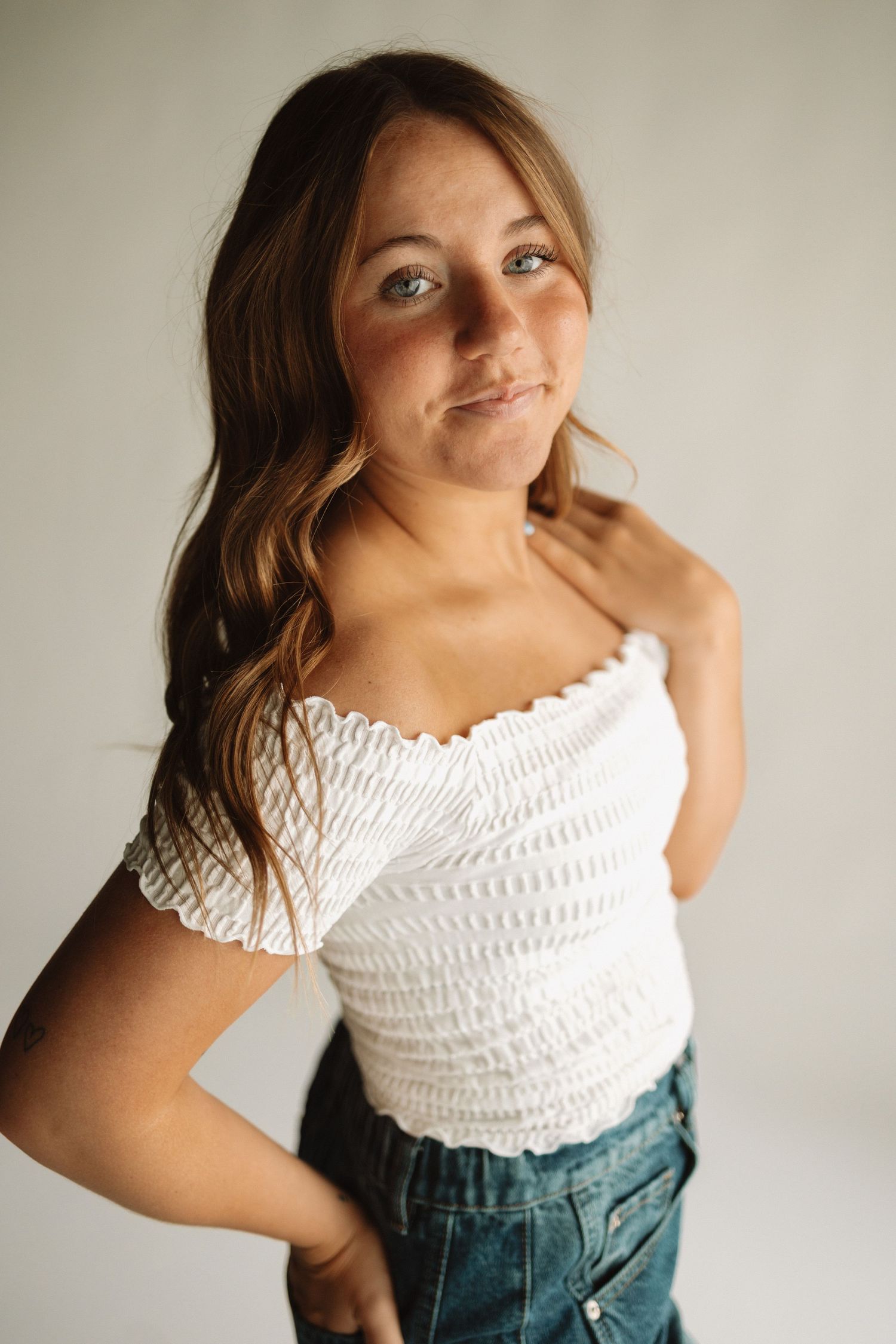 Lifestyle portrait showing feminine summer style with smocked top and high-waisted jeans.