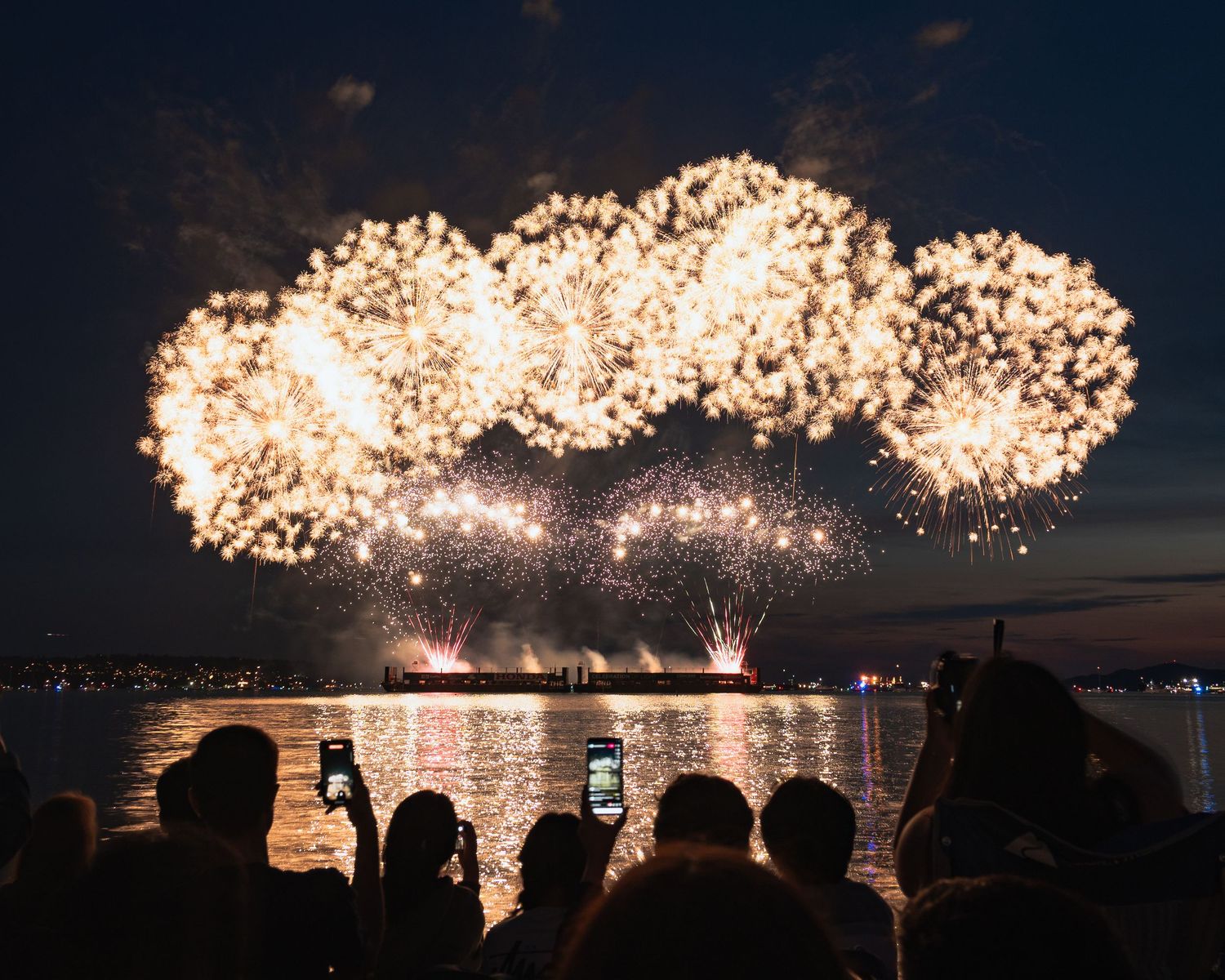 Crowds sitting on beach watching colorful sky show at Vancouver fireworks festival