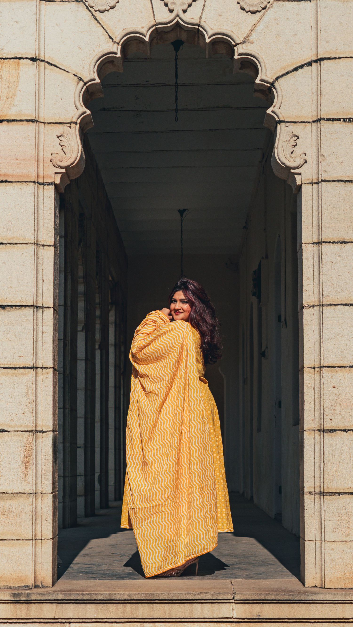 Modern Indian look in yellow dress with traditional jewelry in historical palace in Vadodara, Gujarat, India